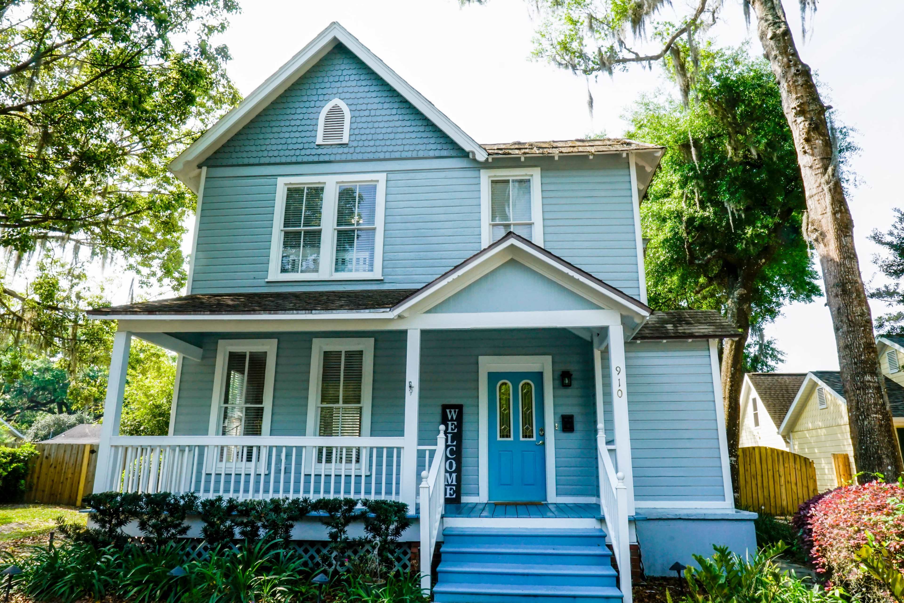 A blue two-story house with a welcoming front porch and a light blue door.