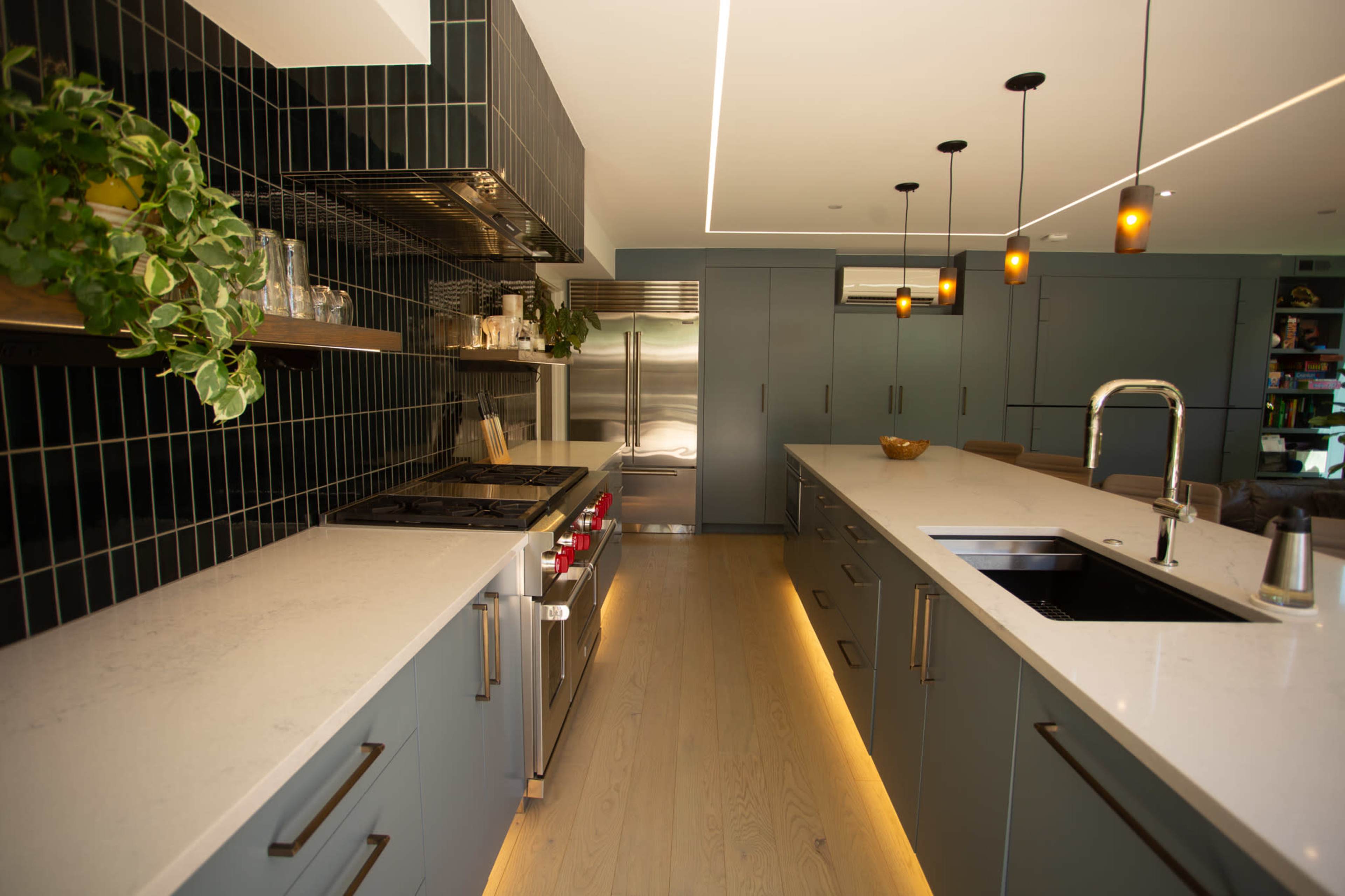 The kitchen features a modern design with dark cabinetry, a stainless steel stove, and a large island with under-cabinet lighting.