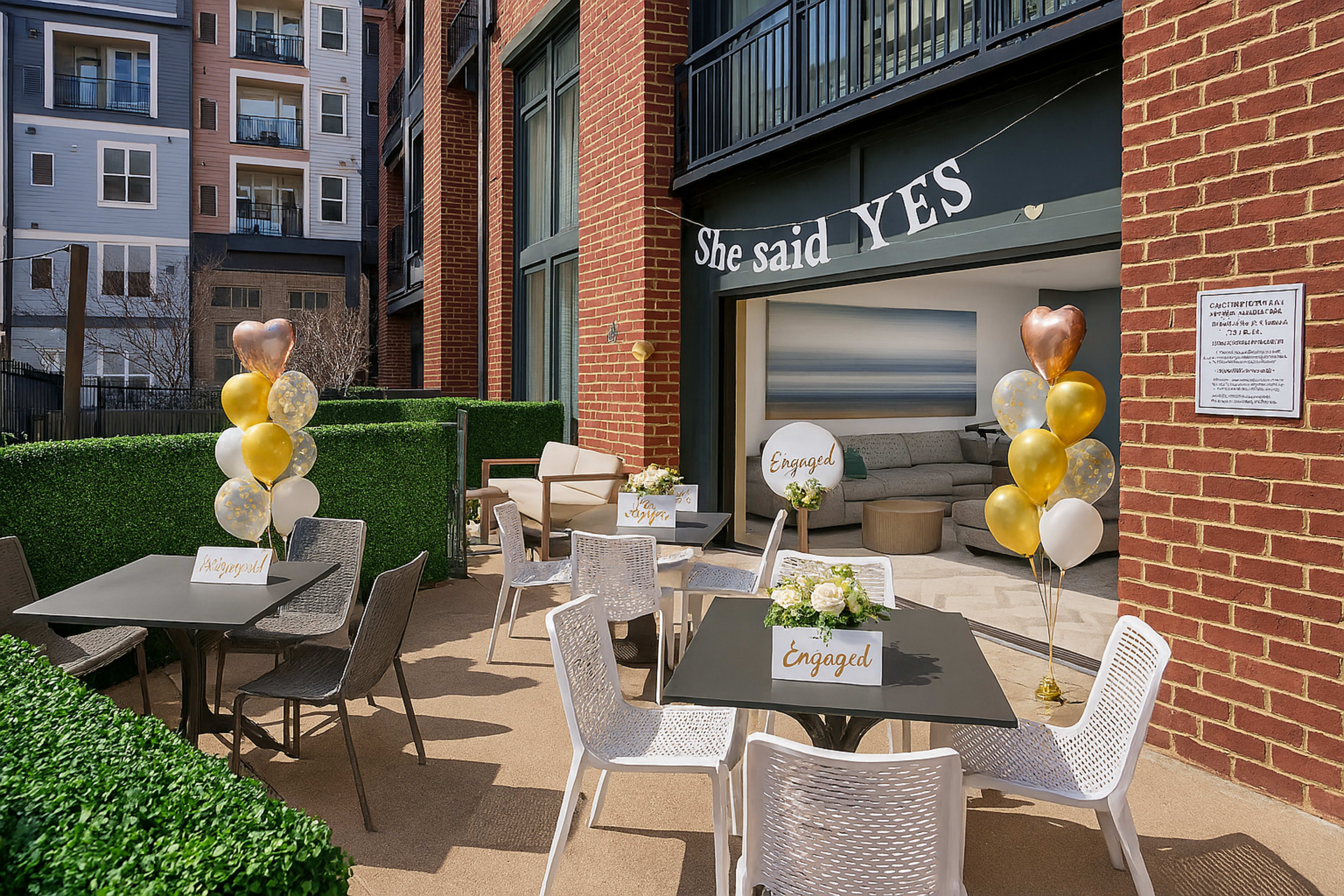 The scene shows an outdoor seating area with tables decorated for an engagement celebration, featuring balloons and signs that read "Engaged" and "Happy."