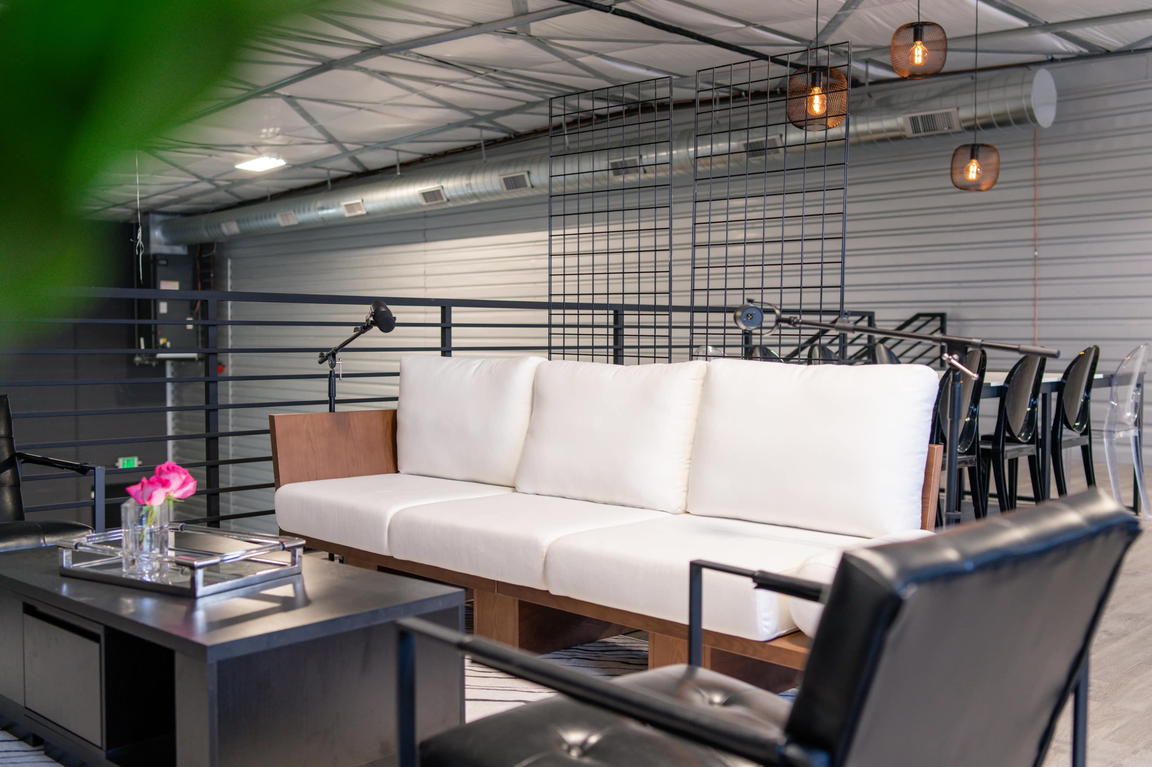 A modern seating area with a white sofa, a black coffee table, and pendant lights in an industrial-style space.