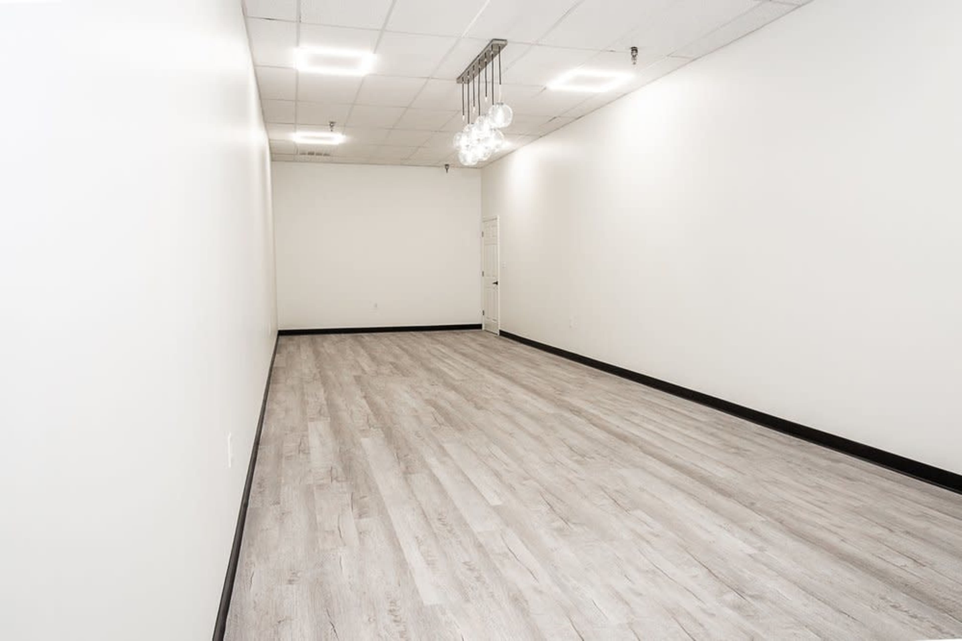 A spacious, empty room with light-colored flooring and white walls.