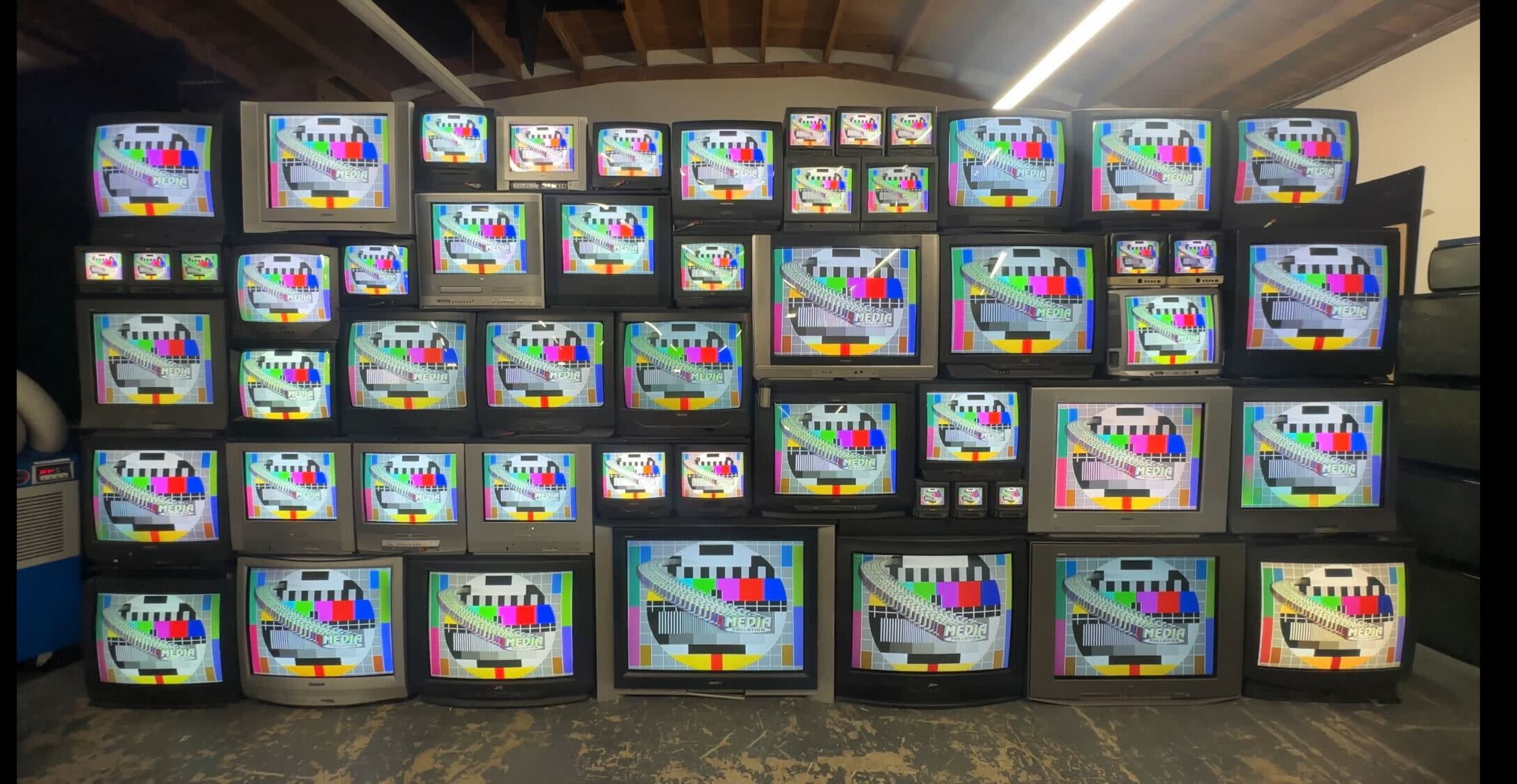 A large wall is covered with multiple old televisions displaying test patterns.