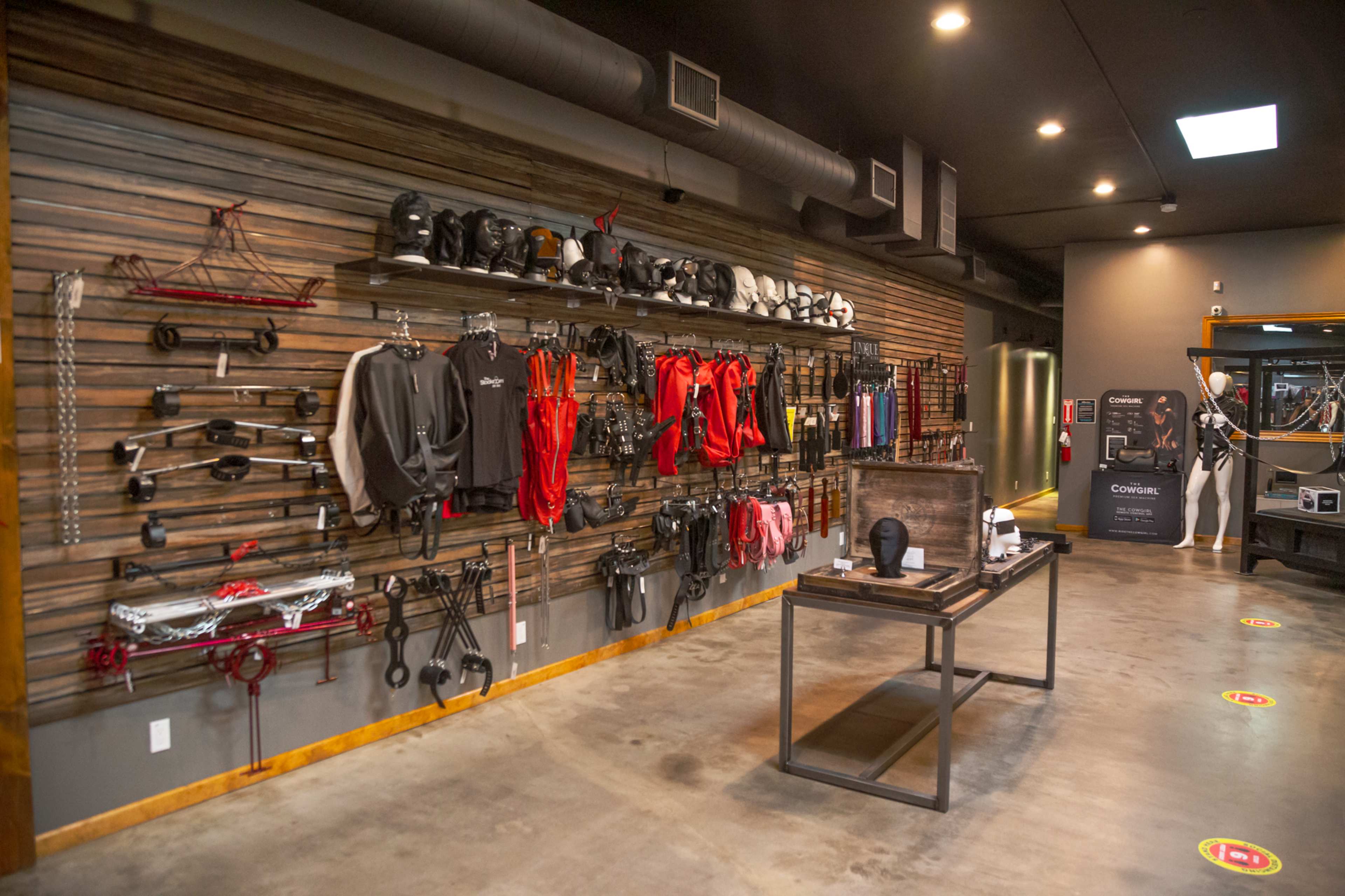 A display wall featuring various pieces of equipment and gear organized on hooks, with a wooden table in the foreground and a modern interior space in the background.