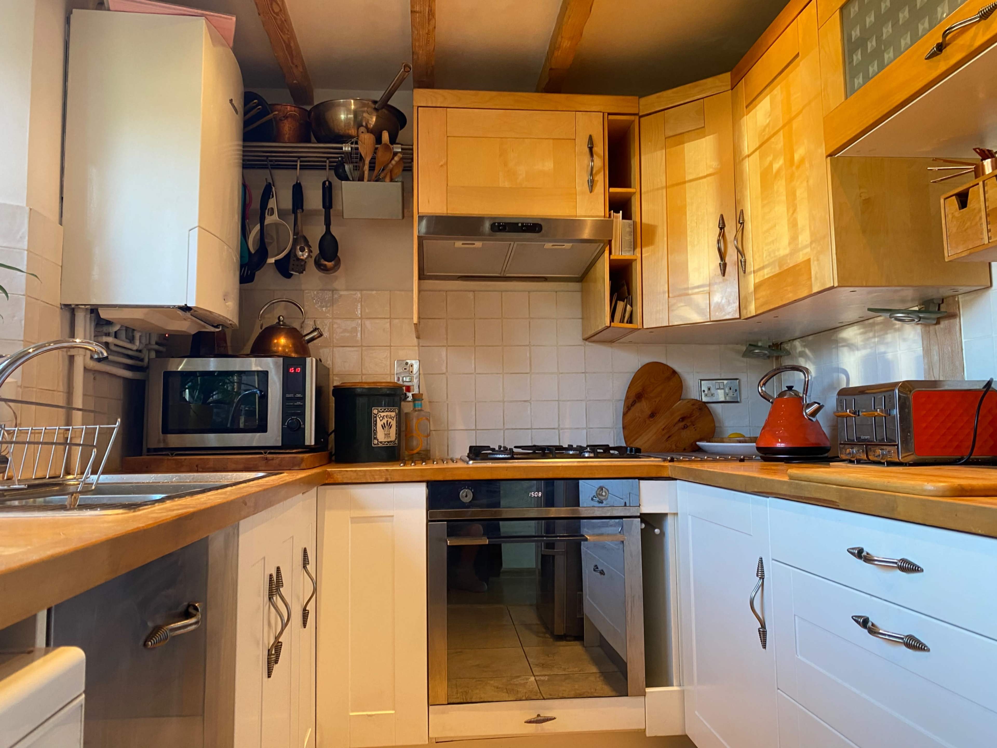 A compact kitchen equipped with wooden cabinets, a stainless steel sink, a microwave, and a stove.