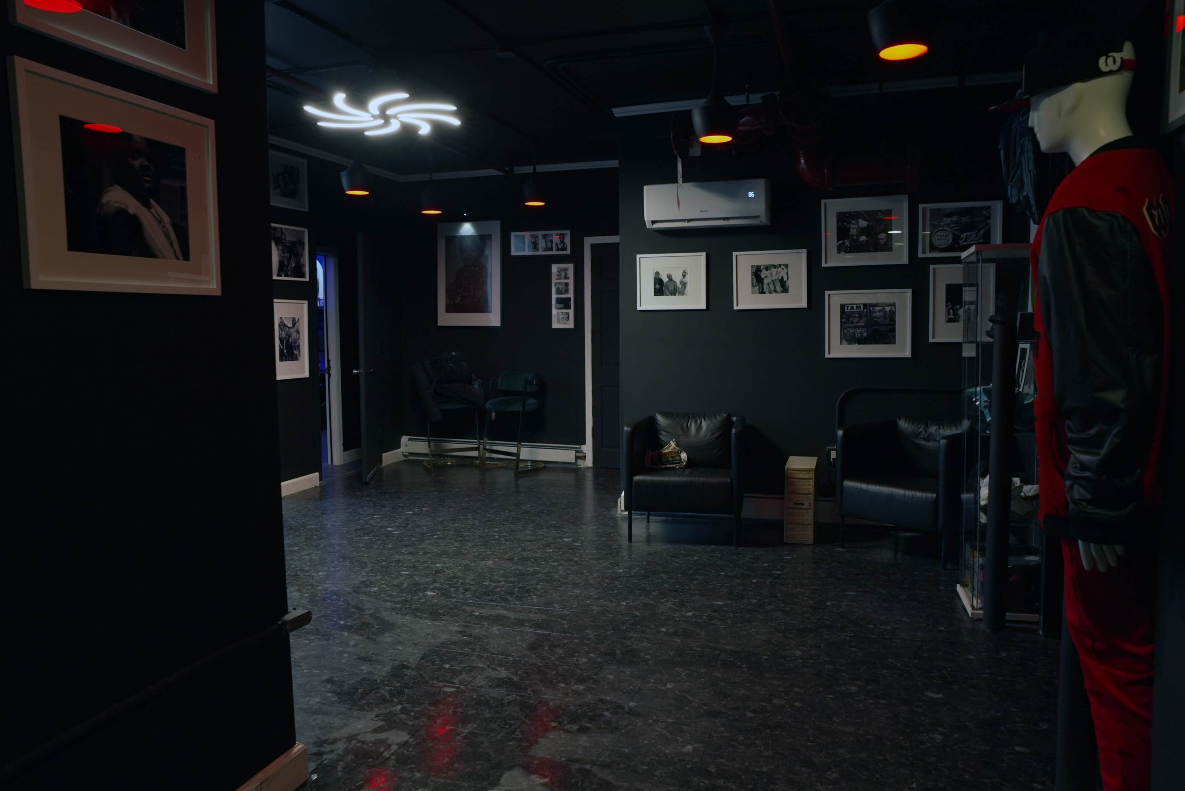 The room features black walls, two leather sofas, and several framed black-and-white photographs hanging on the walls.