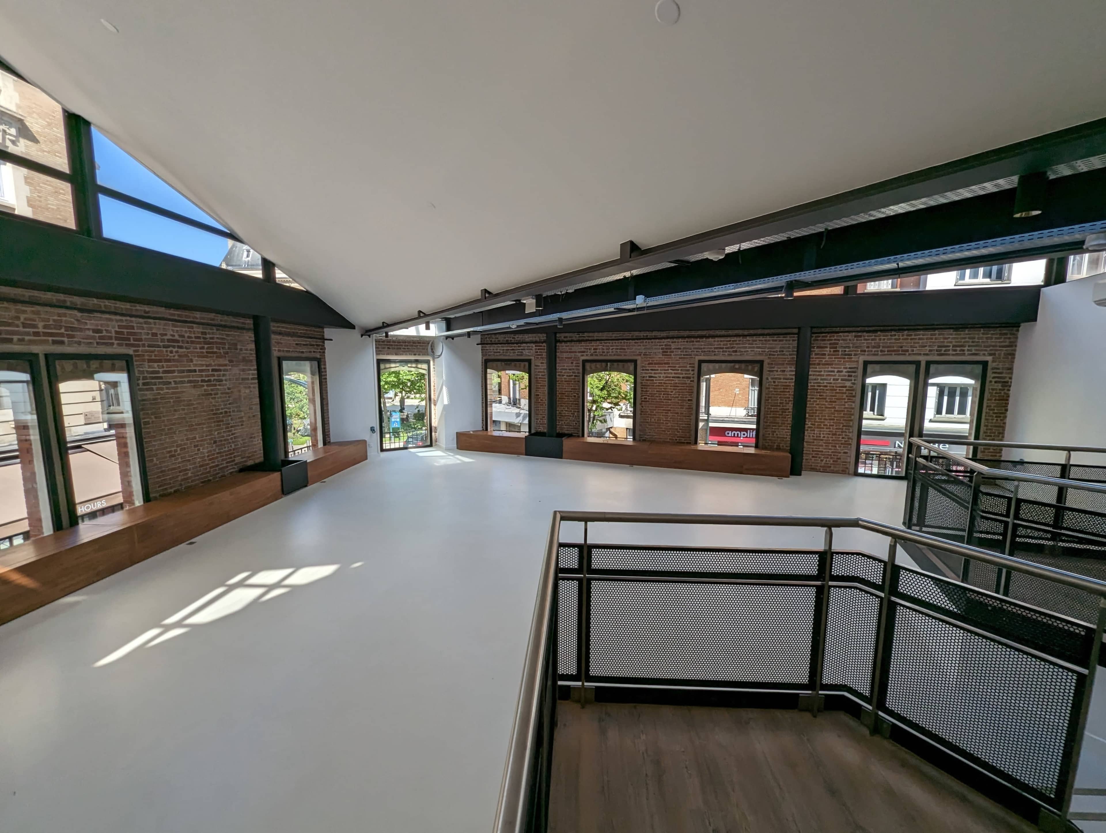 An open, spacious interior with high ceilings, large windows, and a blend of brick and modern architectural elements.