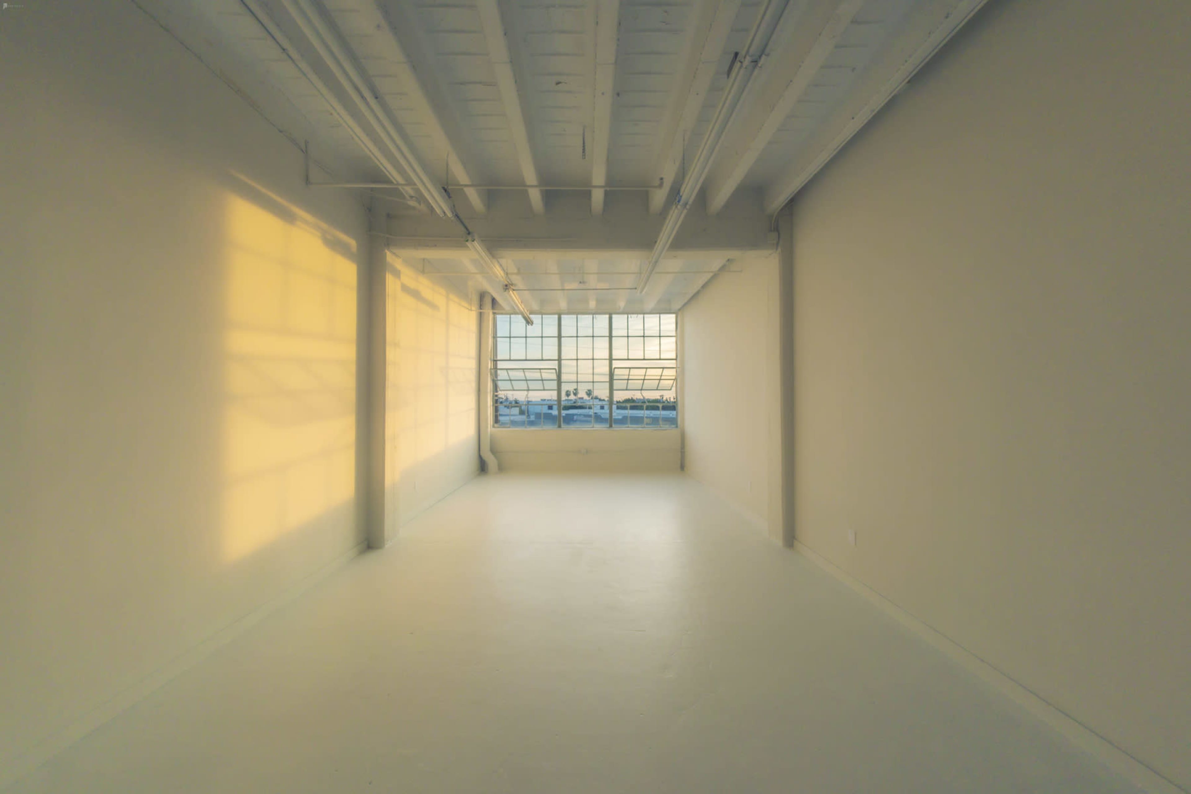 A spacious, empty room with large windows allowing light to stream in and a view of the outside.
