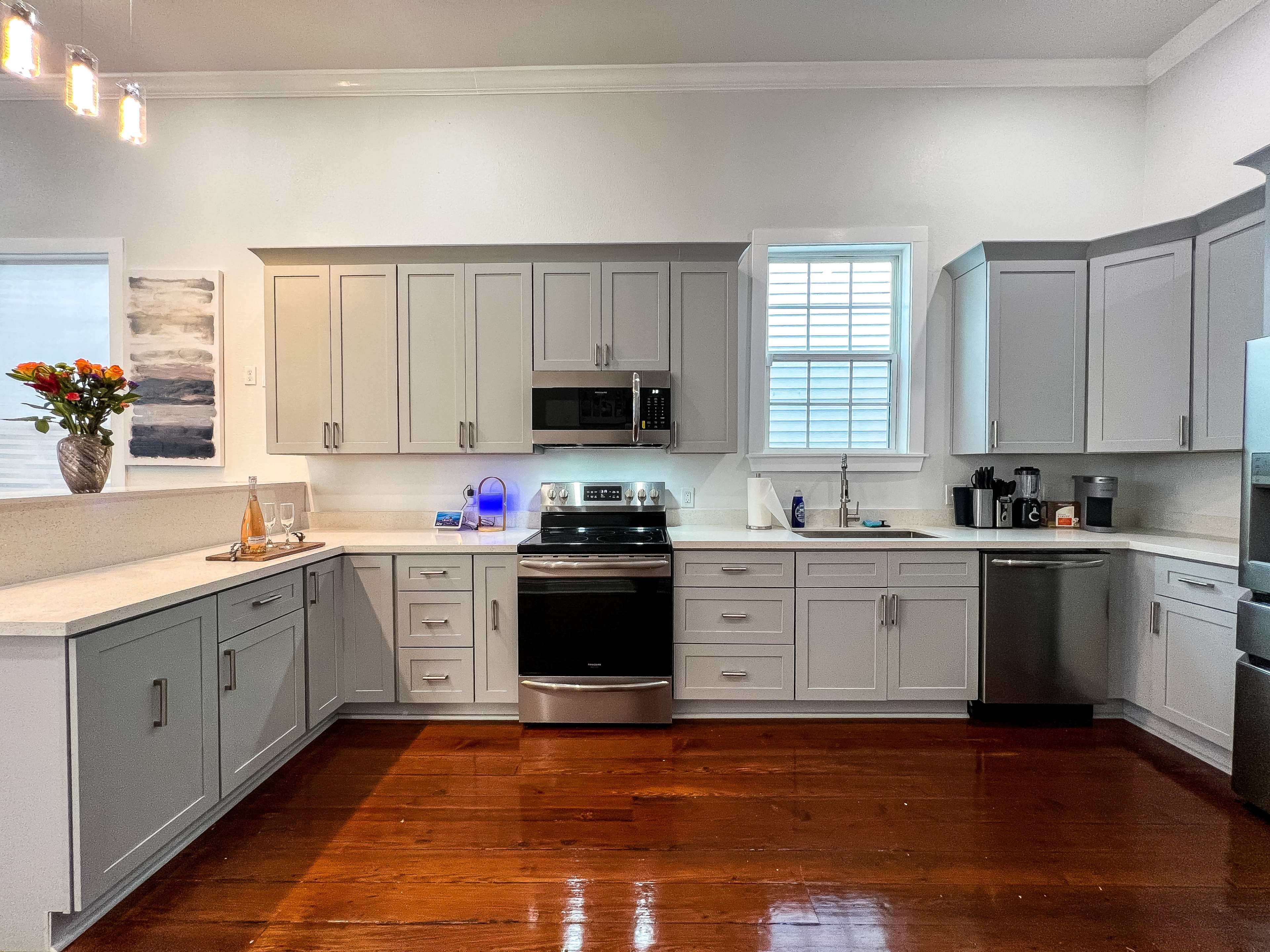 A modern kitchen with gray cabinets, stainless steel appliances, and a wooden floor.