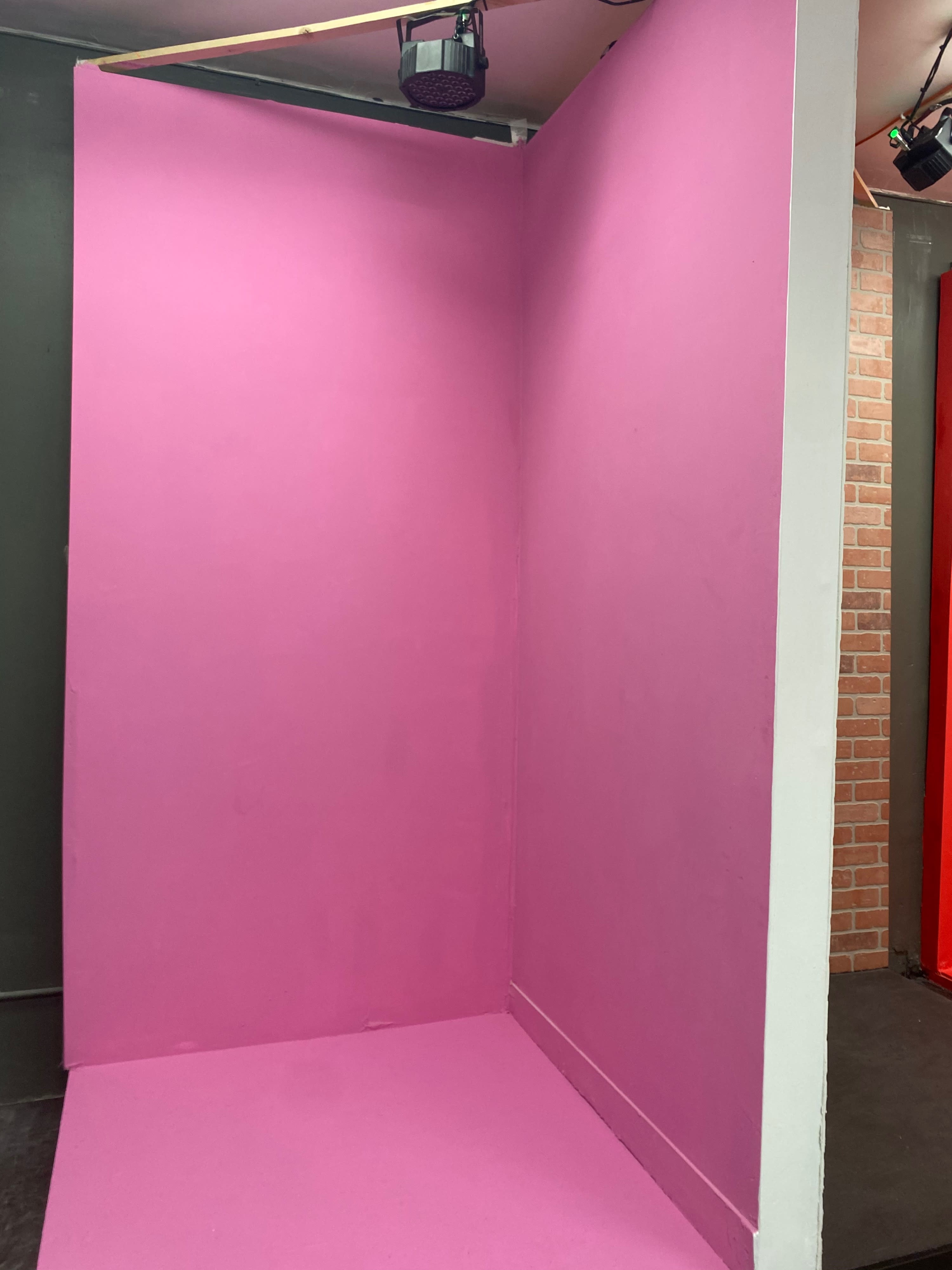 A corner of a room with two pink walls forming a right angle and a gray floor.