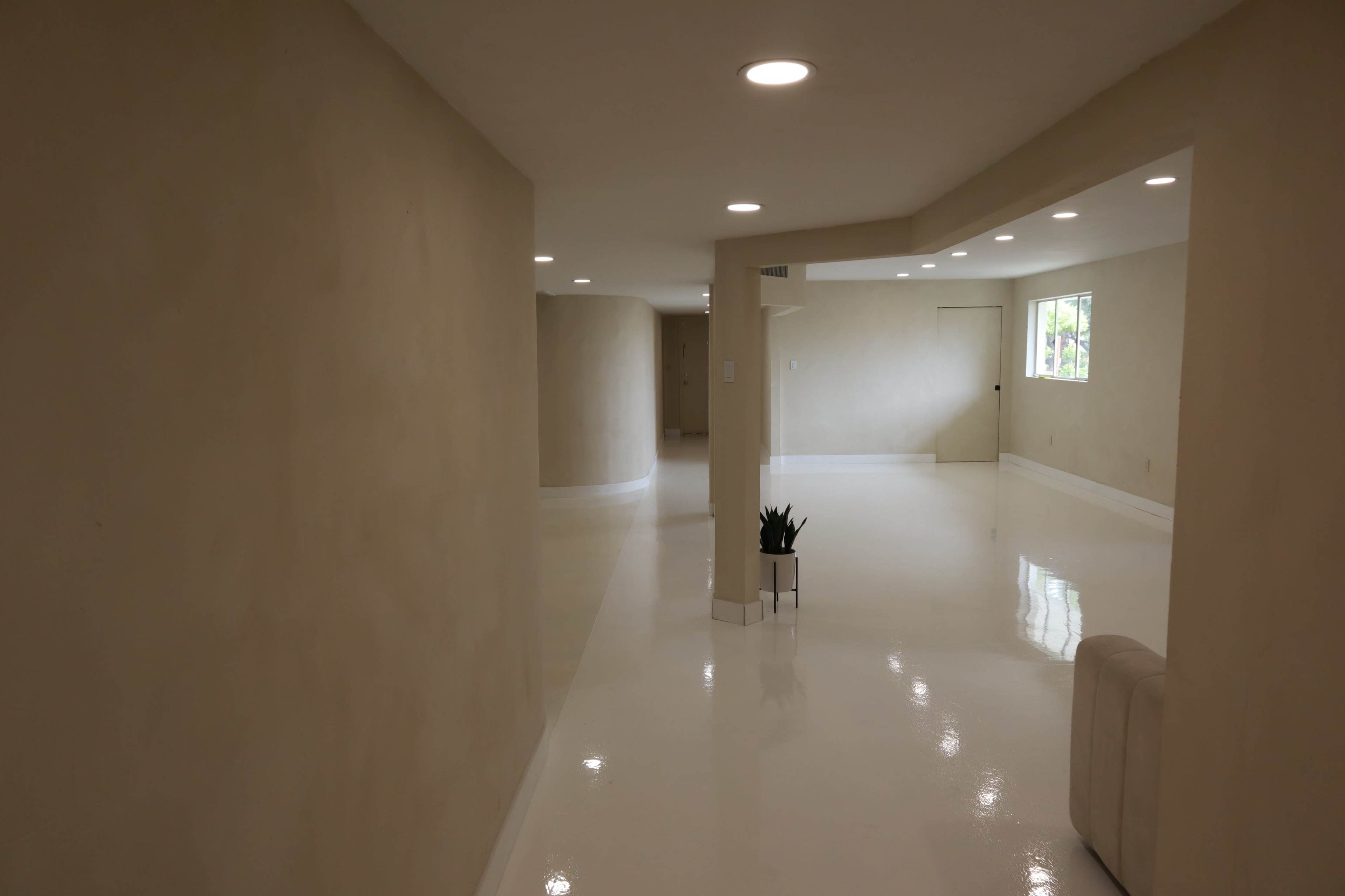 The image shows a spacious, brightly lit interior with smooth, glossy white floors and neutral-colored walls.