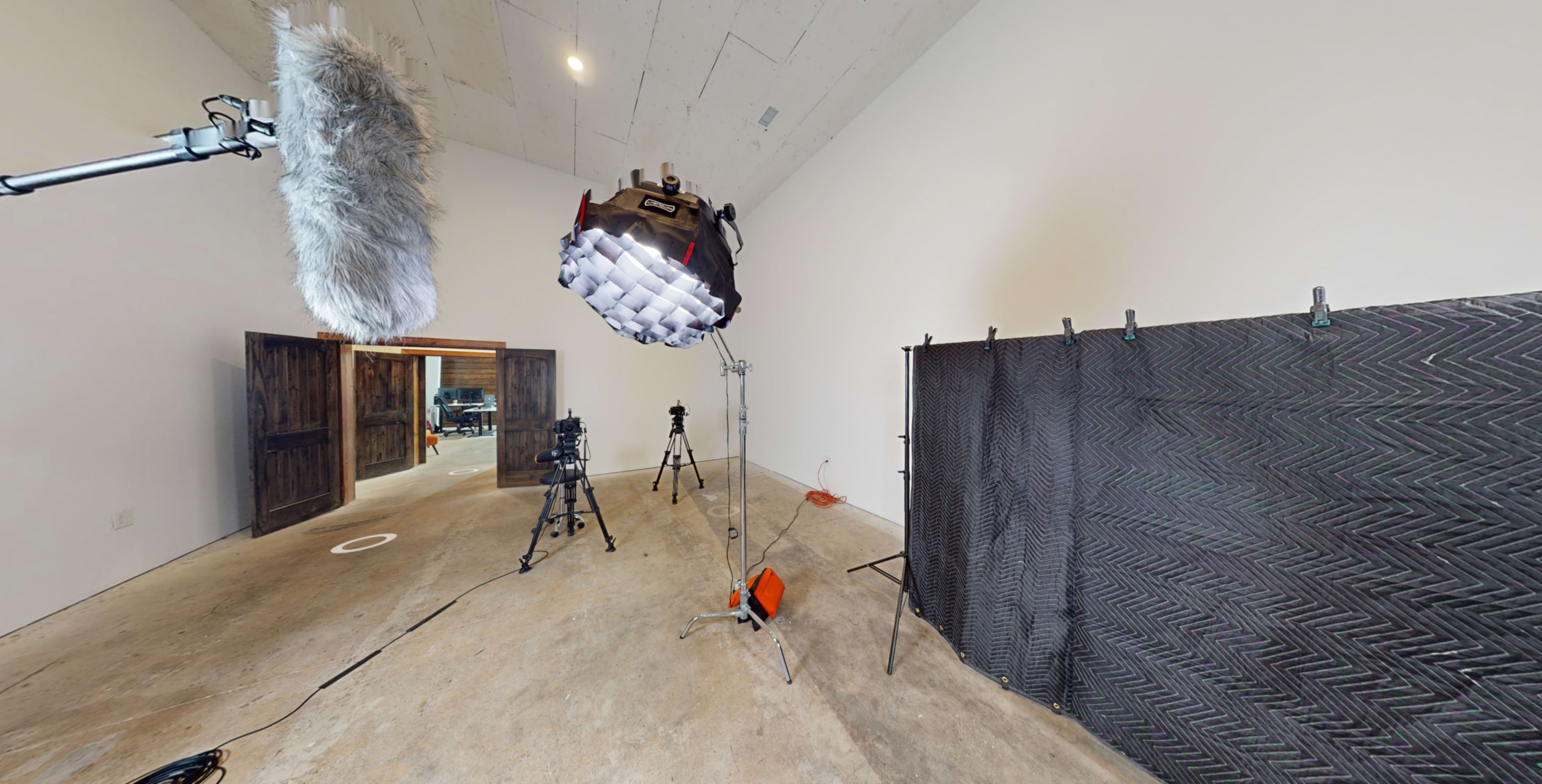 A film studio setup with cameras, lighting equipment, and sound recording gear arranged in an unfinished room.