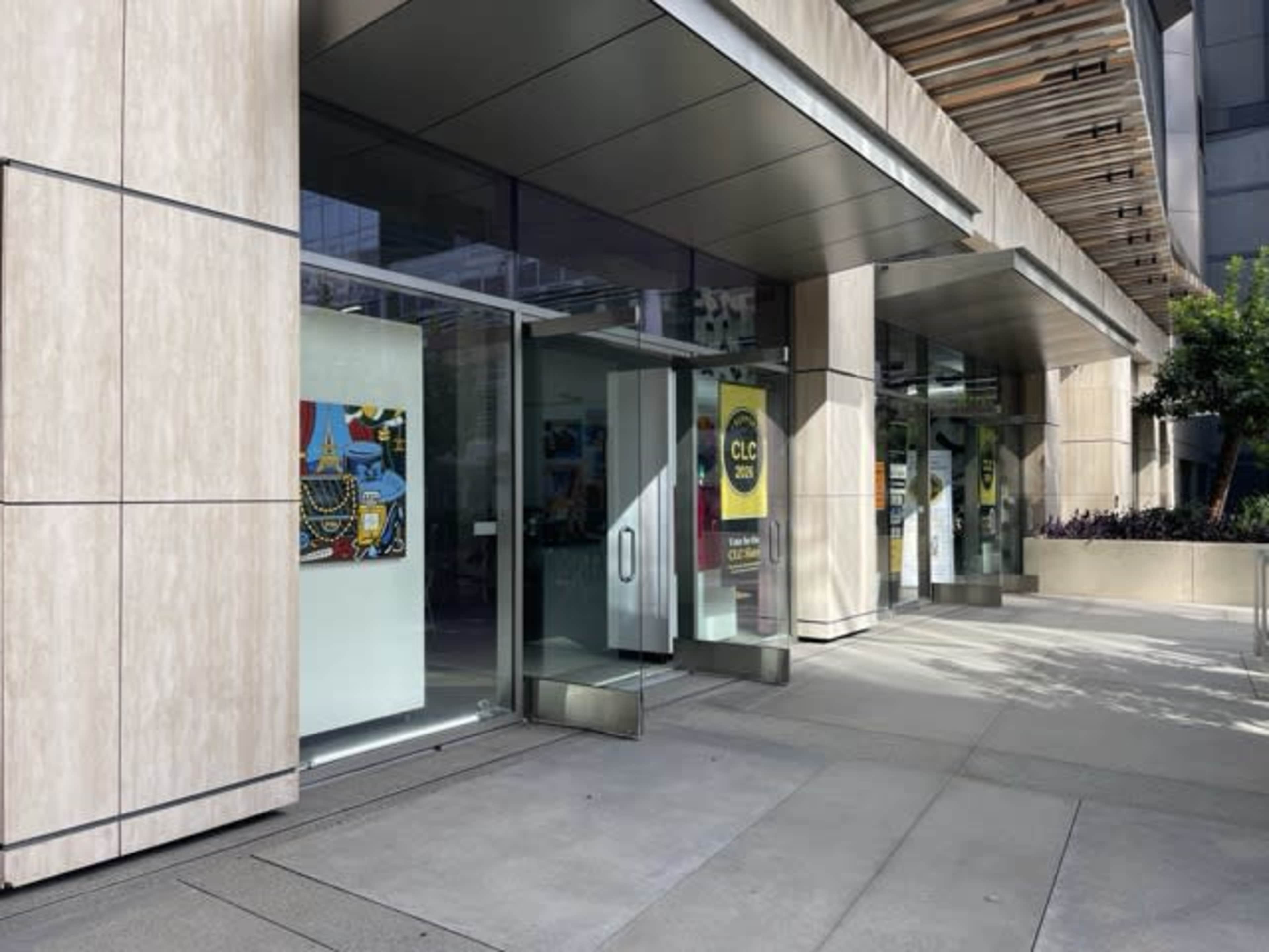 The image shows the entrance of a modern building with glass doors and decorative artwork visible in the windows.