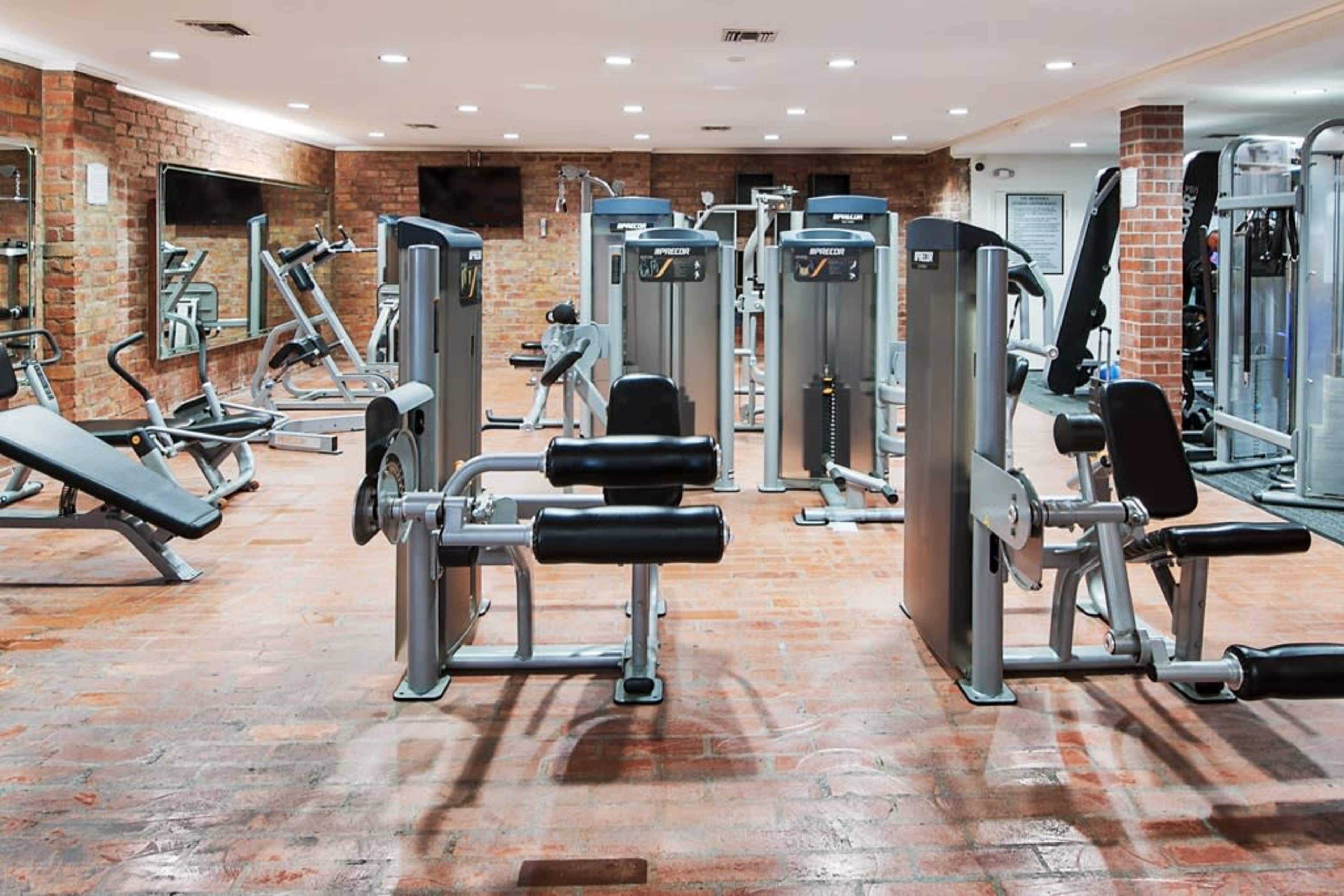 The image shows a well-equipped gym with various exercise machines and free weights arranged in a spacious layout.