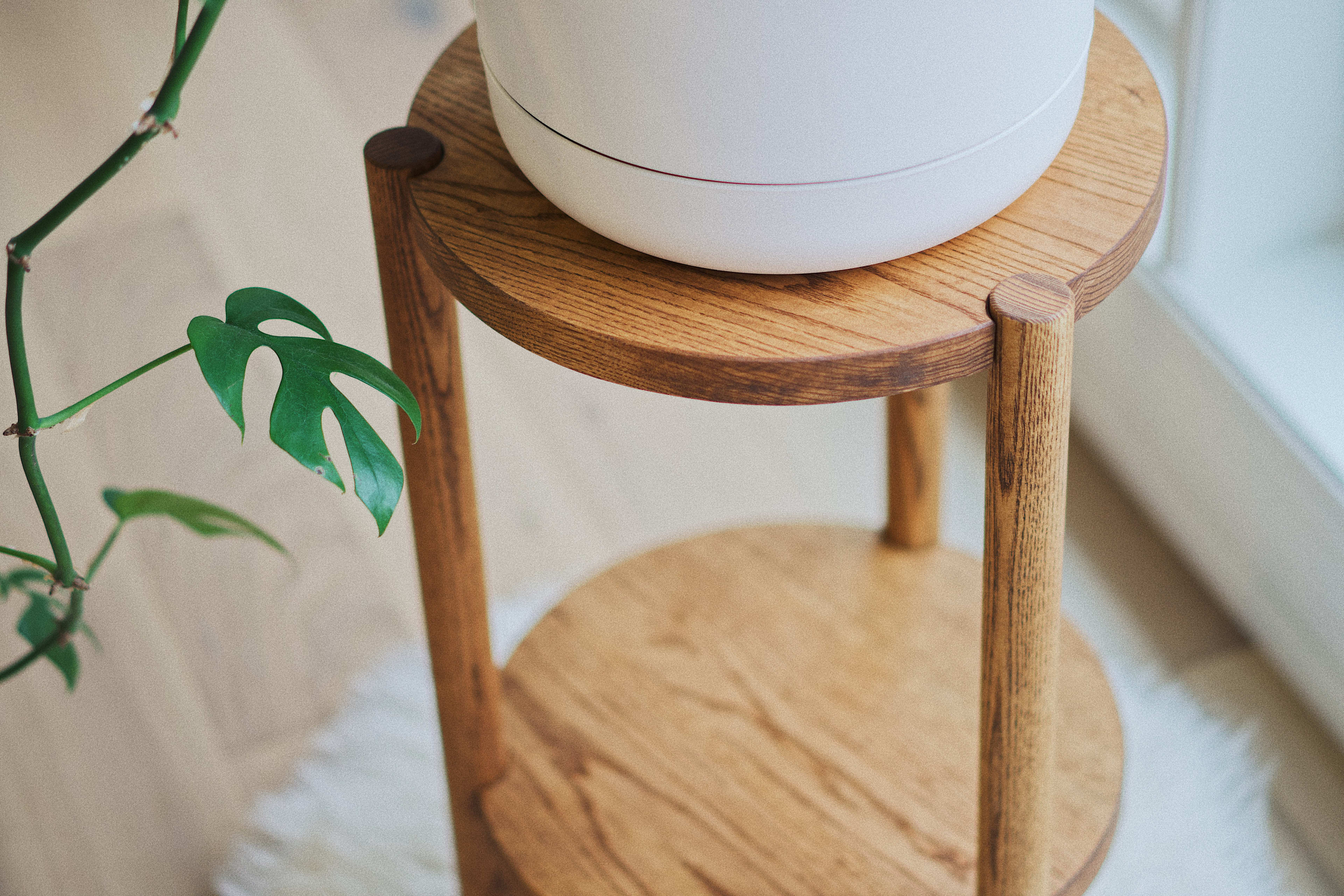 Una maceta beige minimalista sobre un soporte de madera para una sesión de fotos de productos.