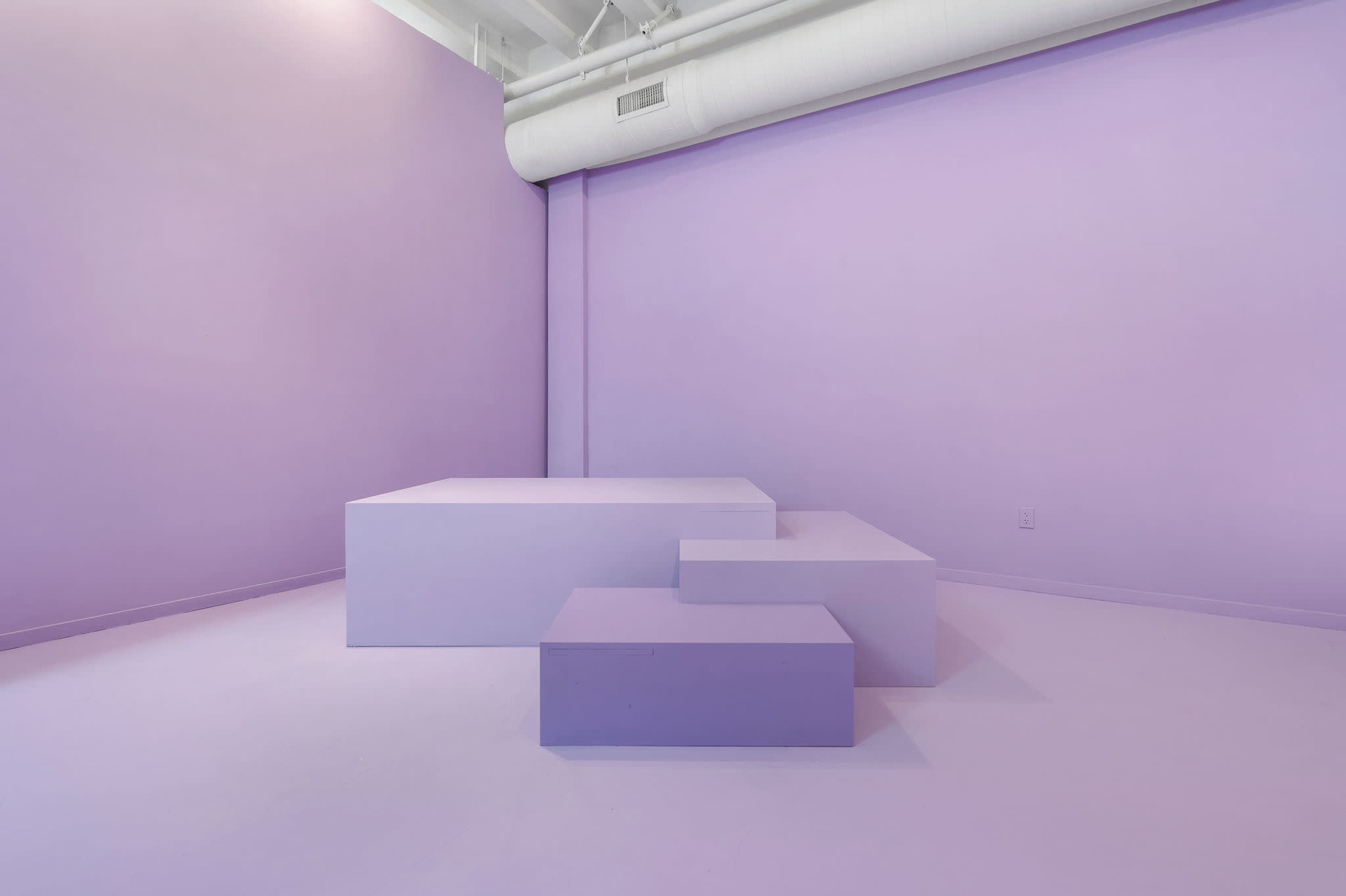 A minimalist room featuring varying sizes of purple geometric shapes against a matching purple wall and floor.