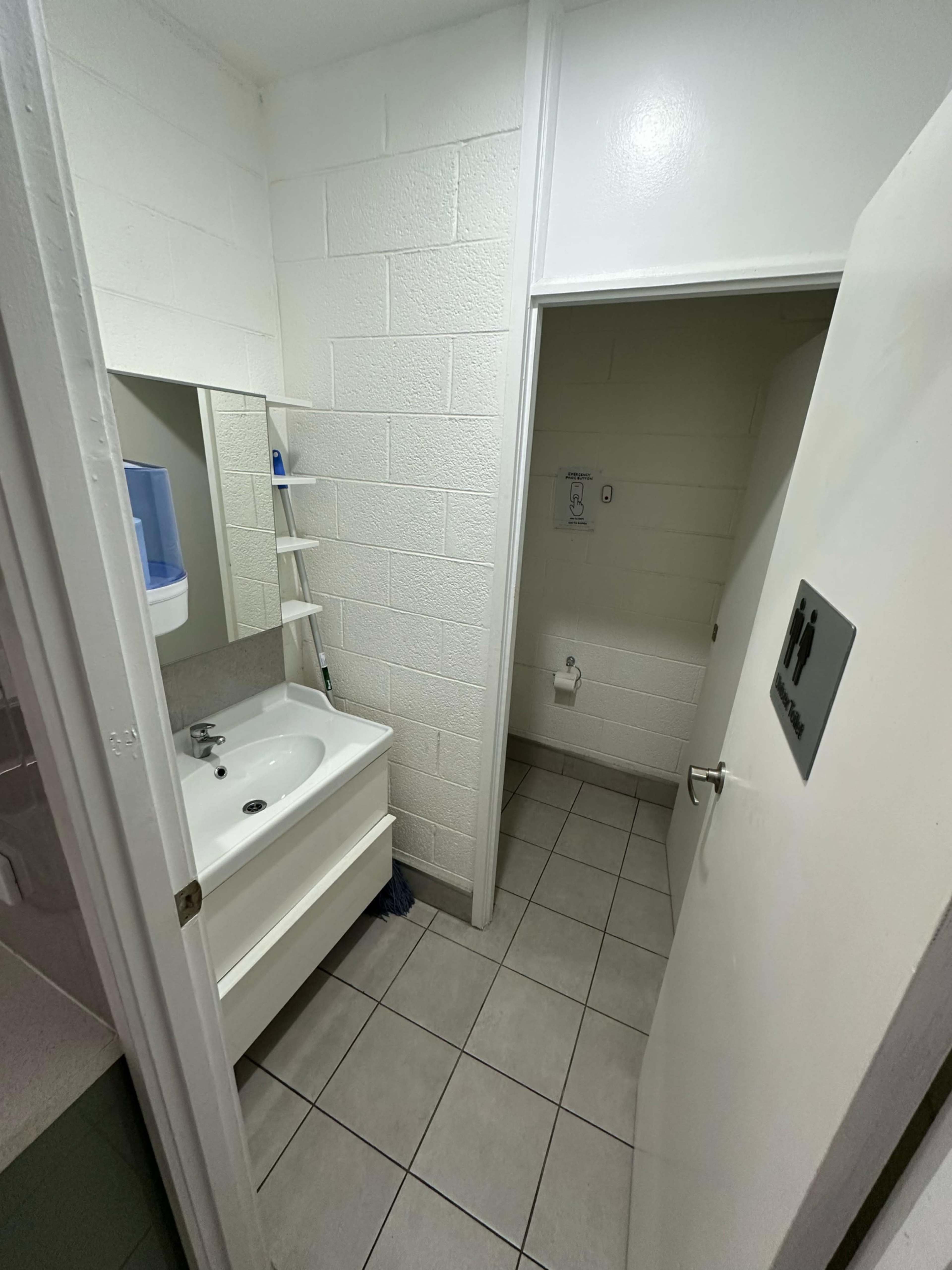 The image shows a small bathroom with a sink, mirror, and a door leading to another room or area.