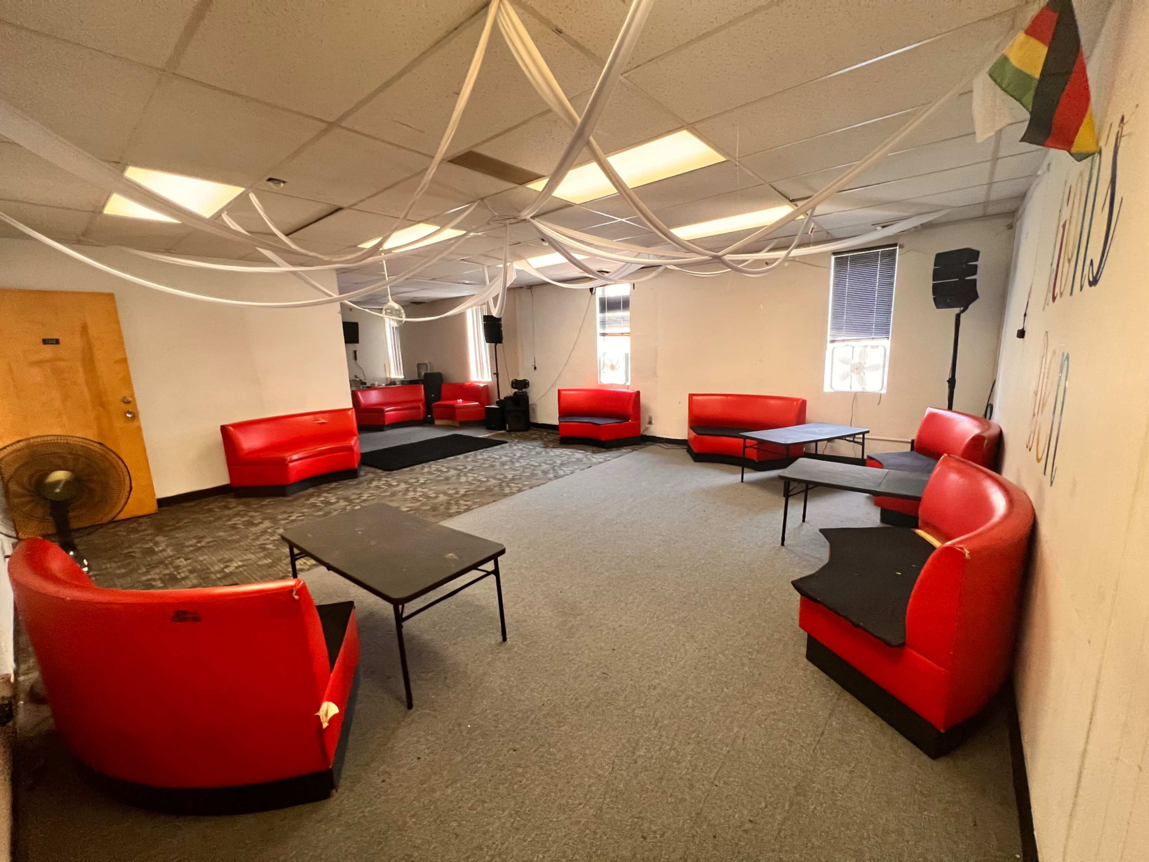 The room features several red seating areas arranged around black tables, with white drapery hanging from the ceiling.