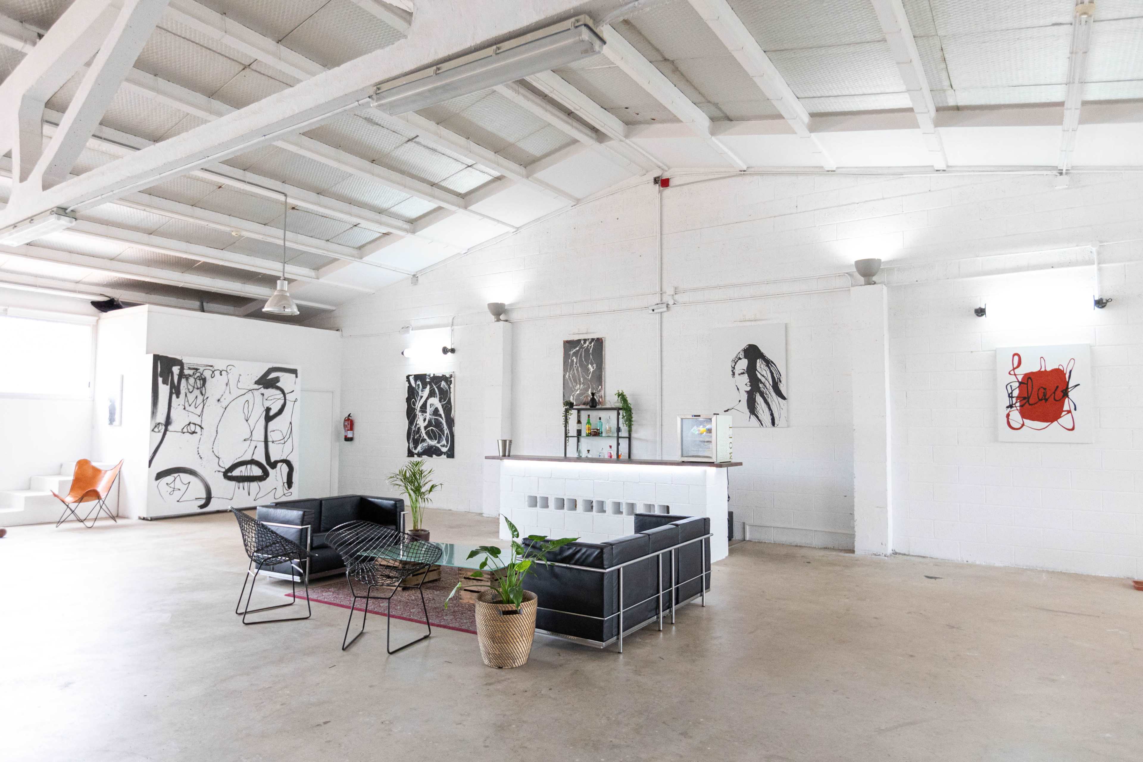 A spacious, minimalist interior with modern furniture, large artwork on the walls, and ample natural light.