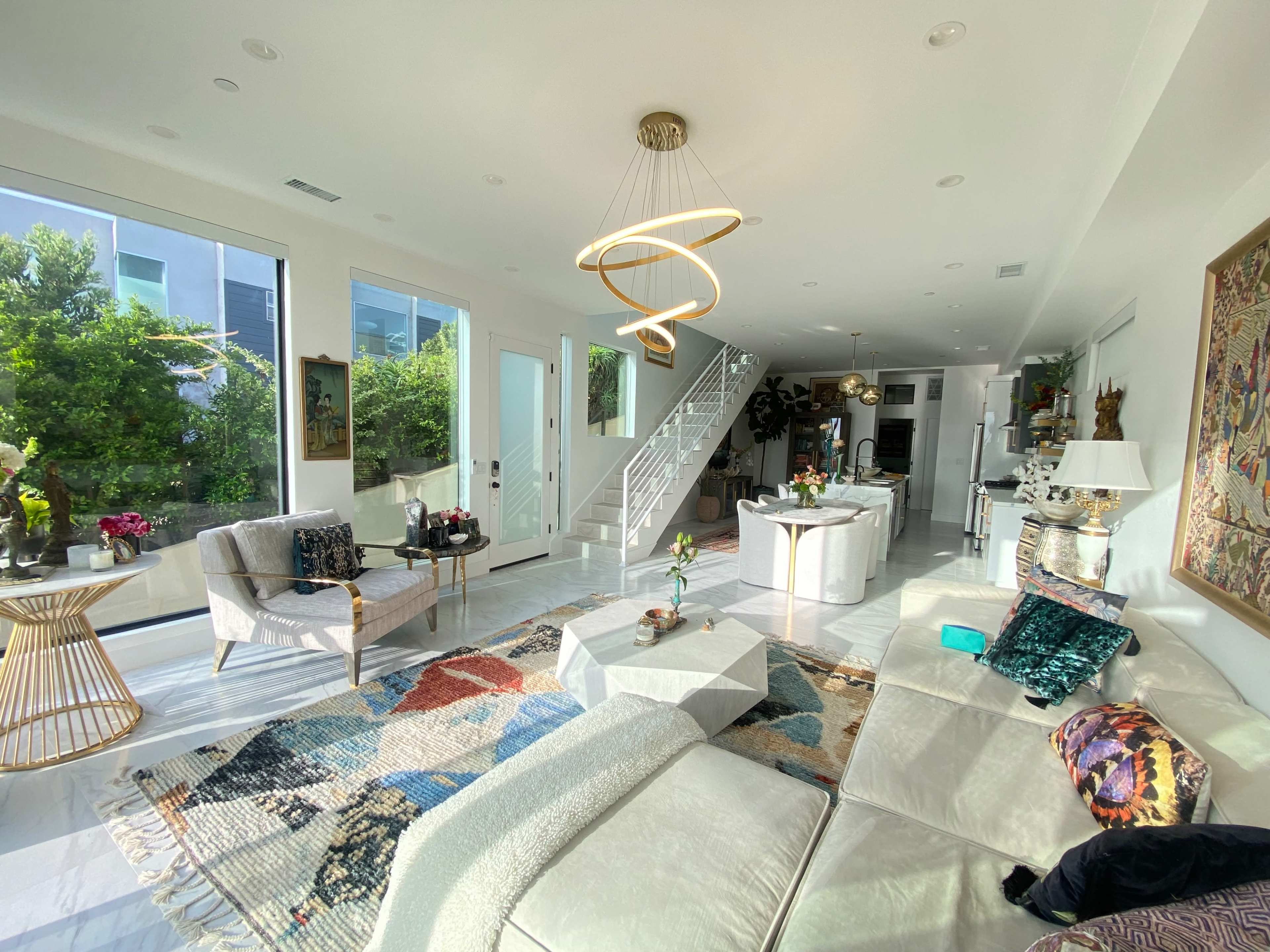 A modern living room adorned with large windows, a patterned rug, a sofa, and minimalist decor.