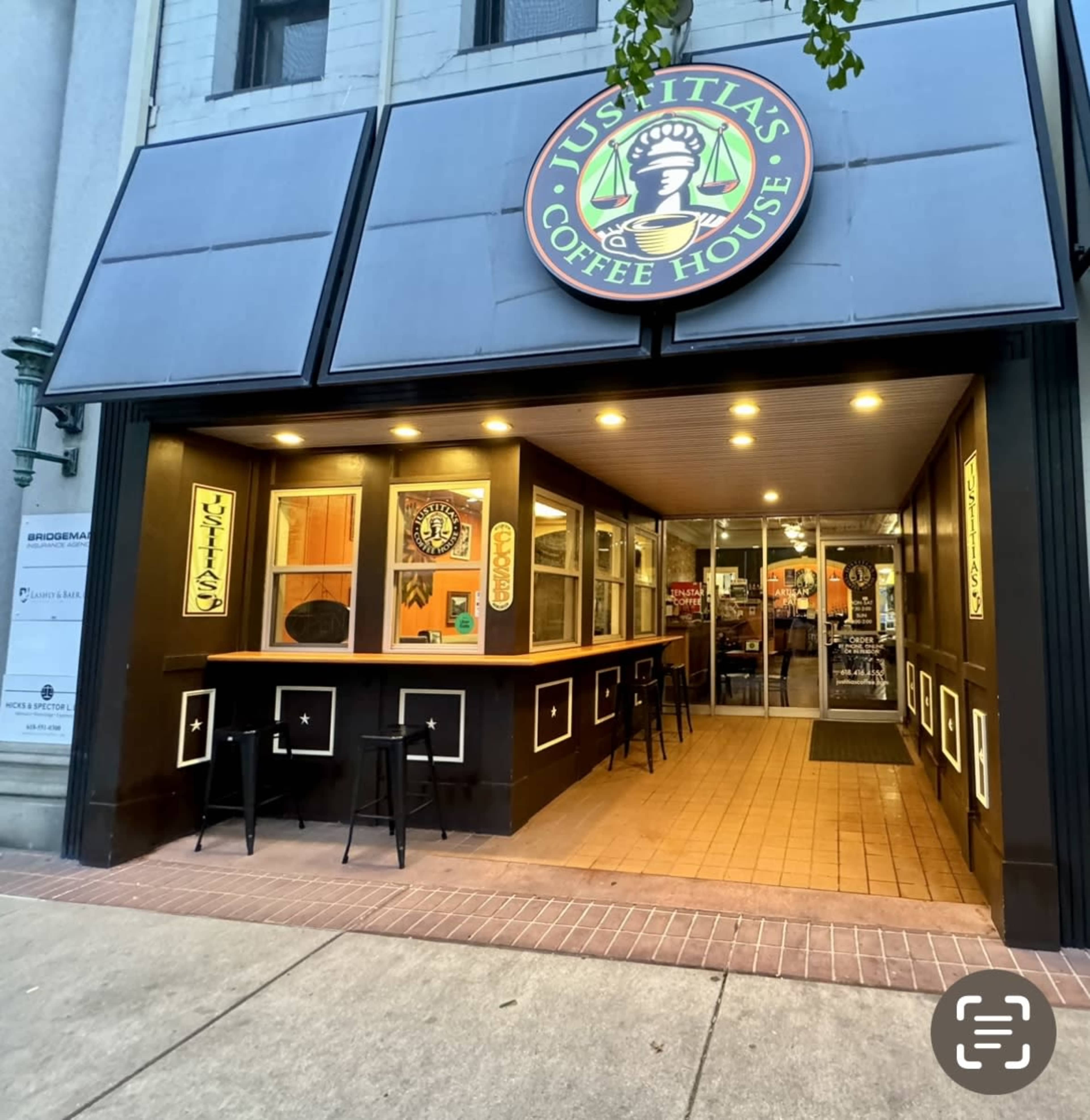 The image shows the entrance of Just Italy's Coffee House featuring a prominent sign, outdoor seating, and illuminated interior details.