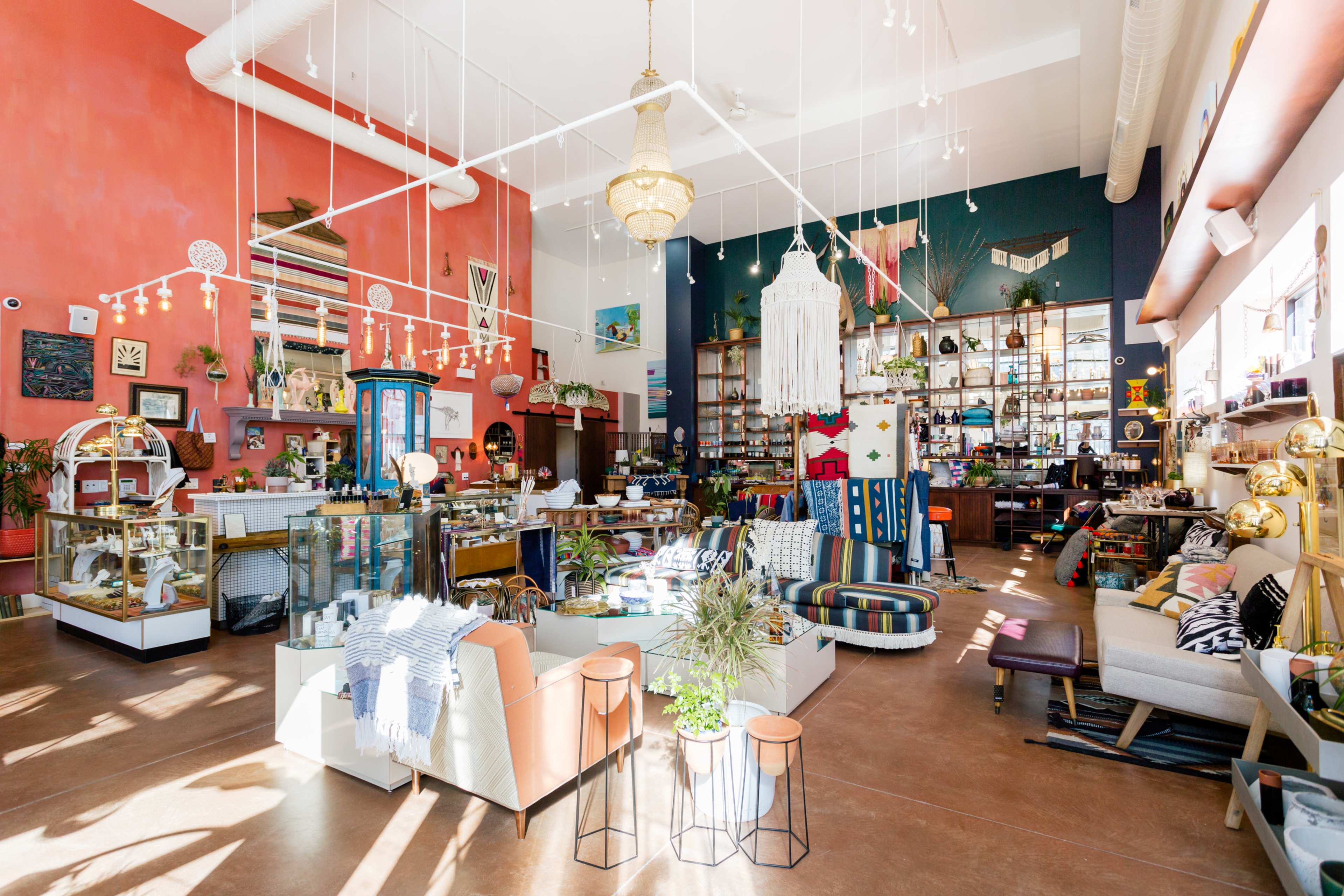 A brightly lit retail space filled with eclectic furniture, decorative items, and displays of various products.