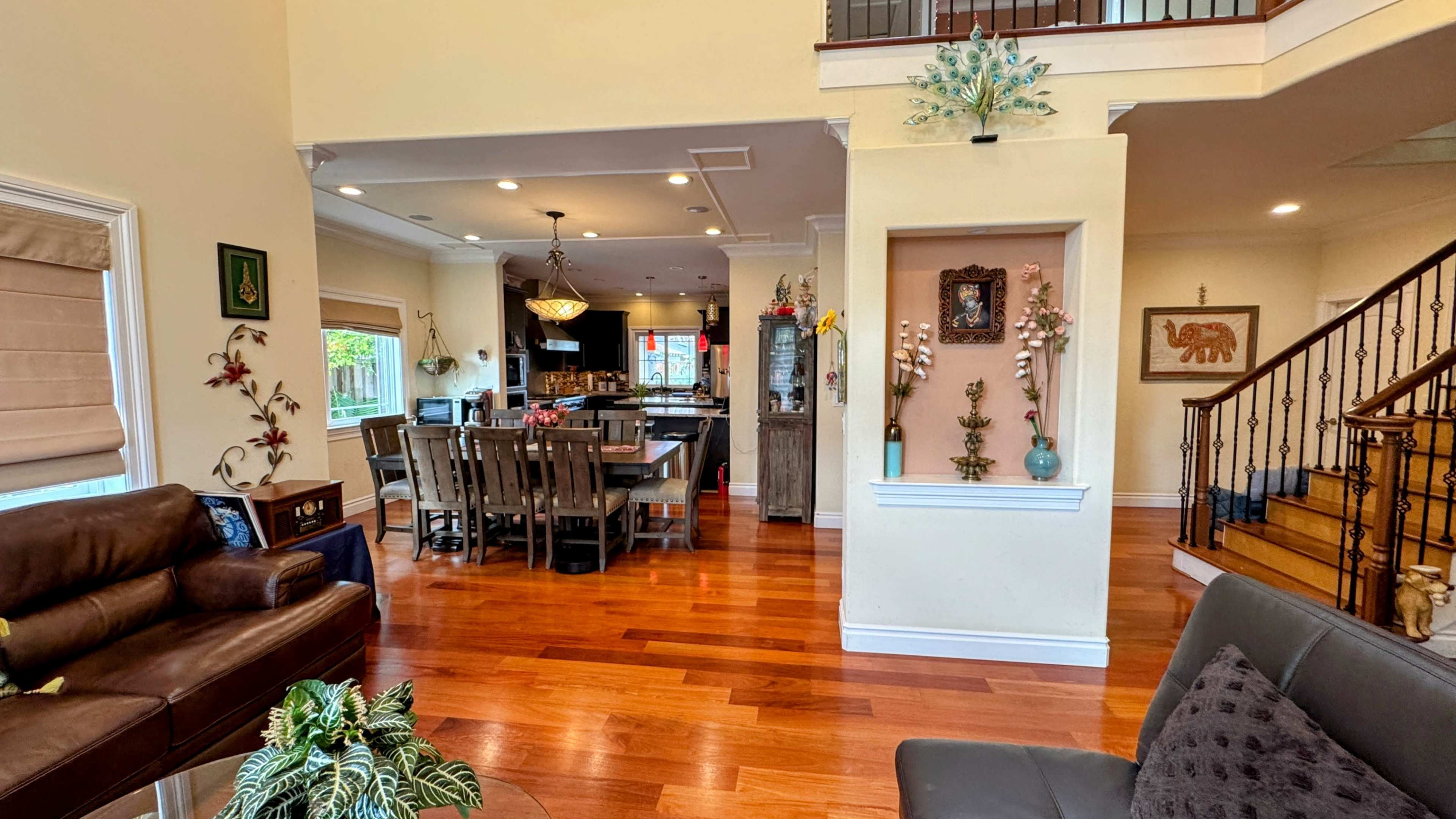 The image shows a spacious living area connected to a dining space, featuring wooden floors and decorative elements on the walls.