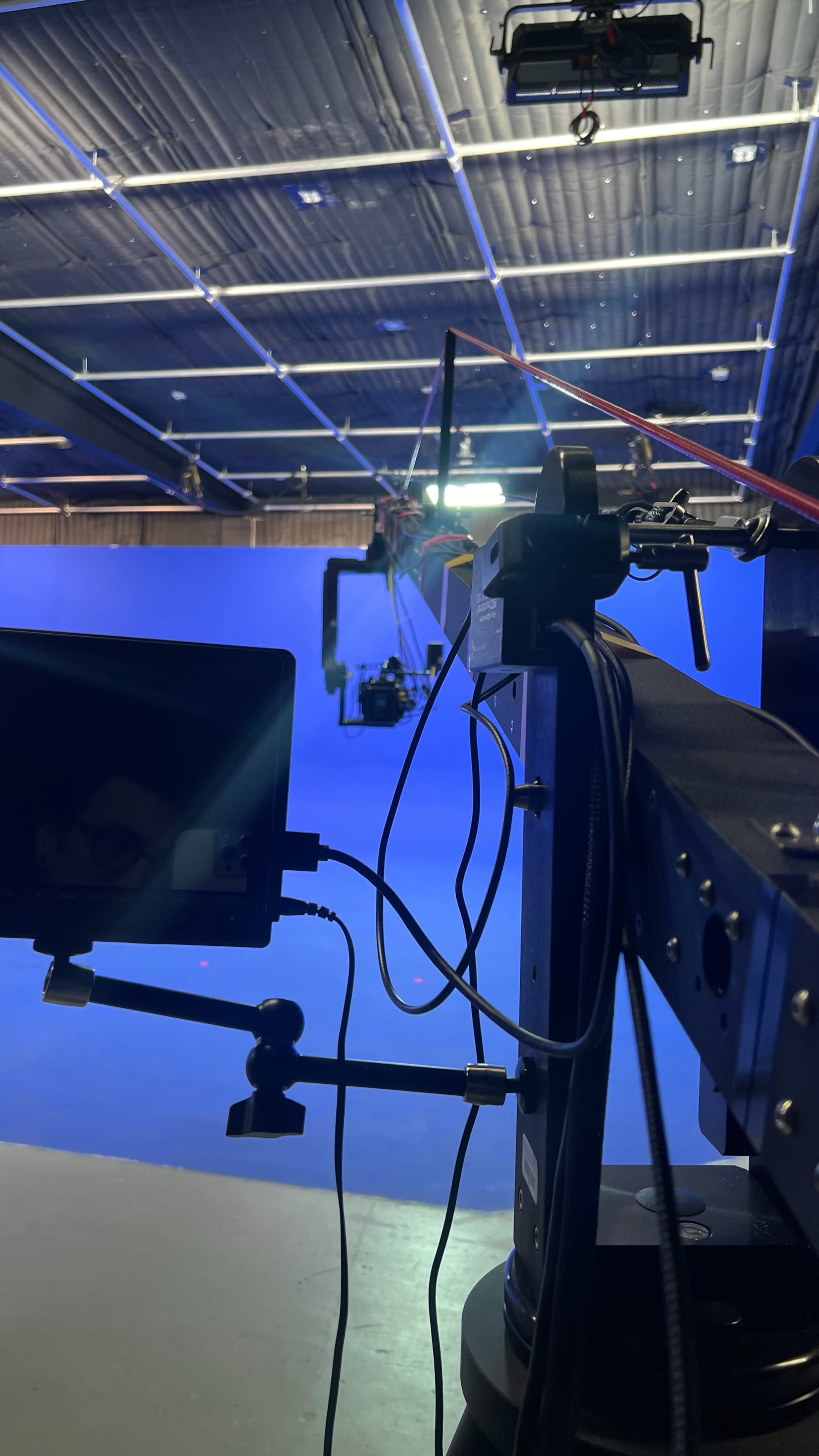 A film production setup featuring a camera on a robotic arm in front of a blue backdrop.