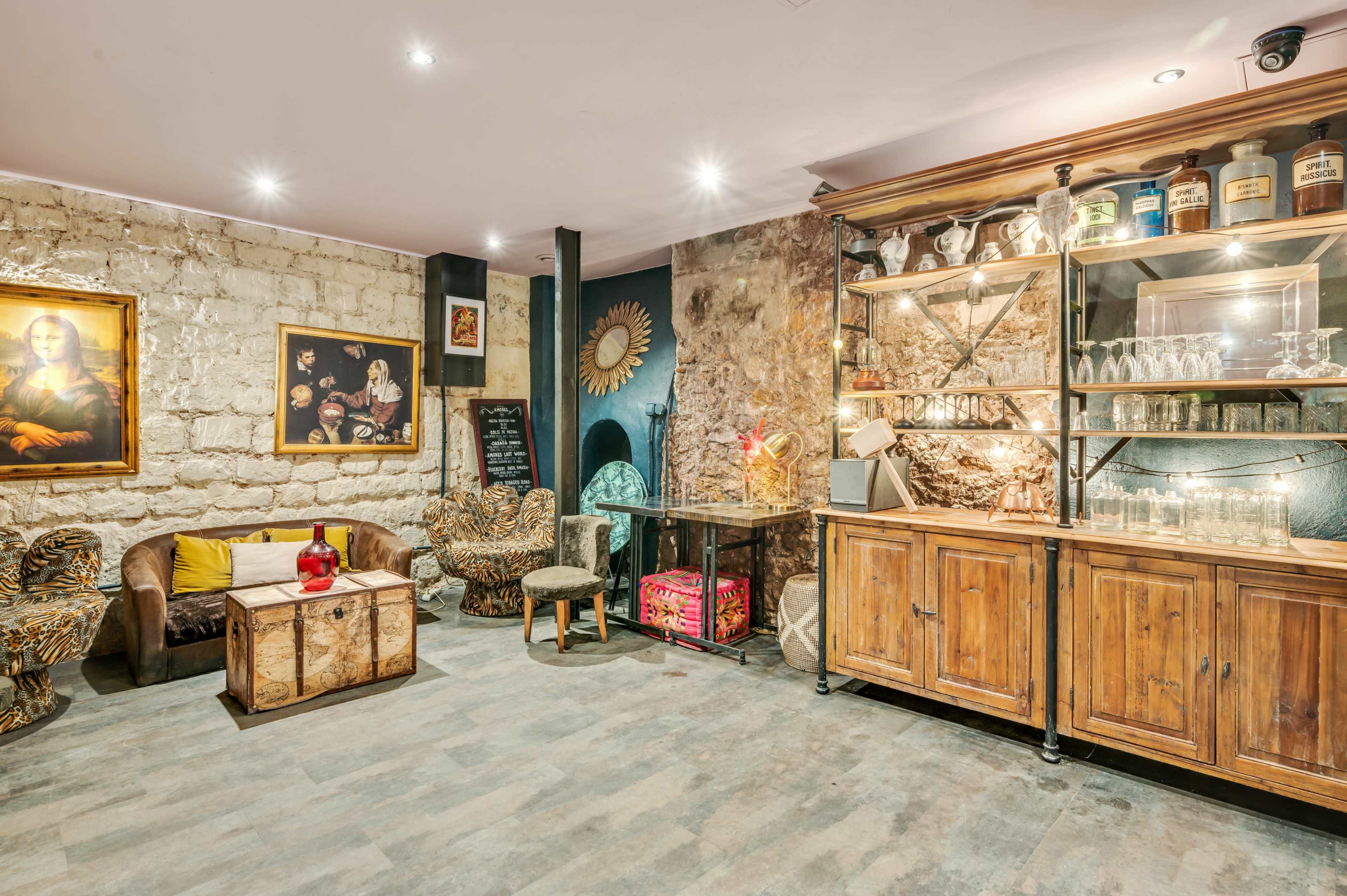 The room features a mix of vintage furniture and decor, including a couch, a wooden cabinet, and an artistic wall with a framed painting.