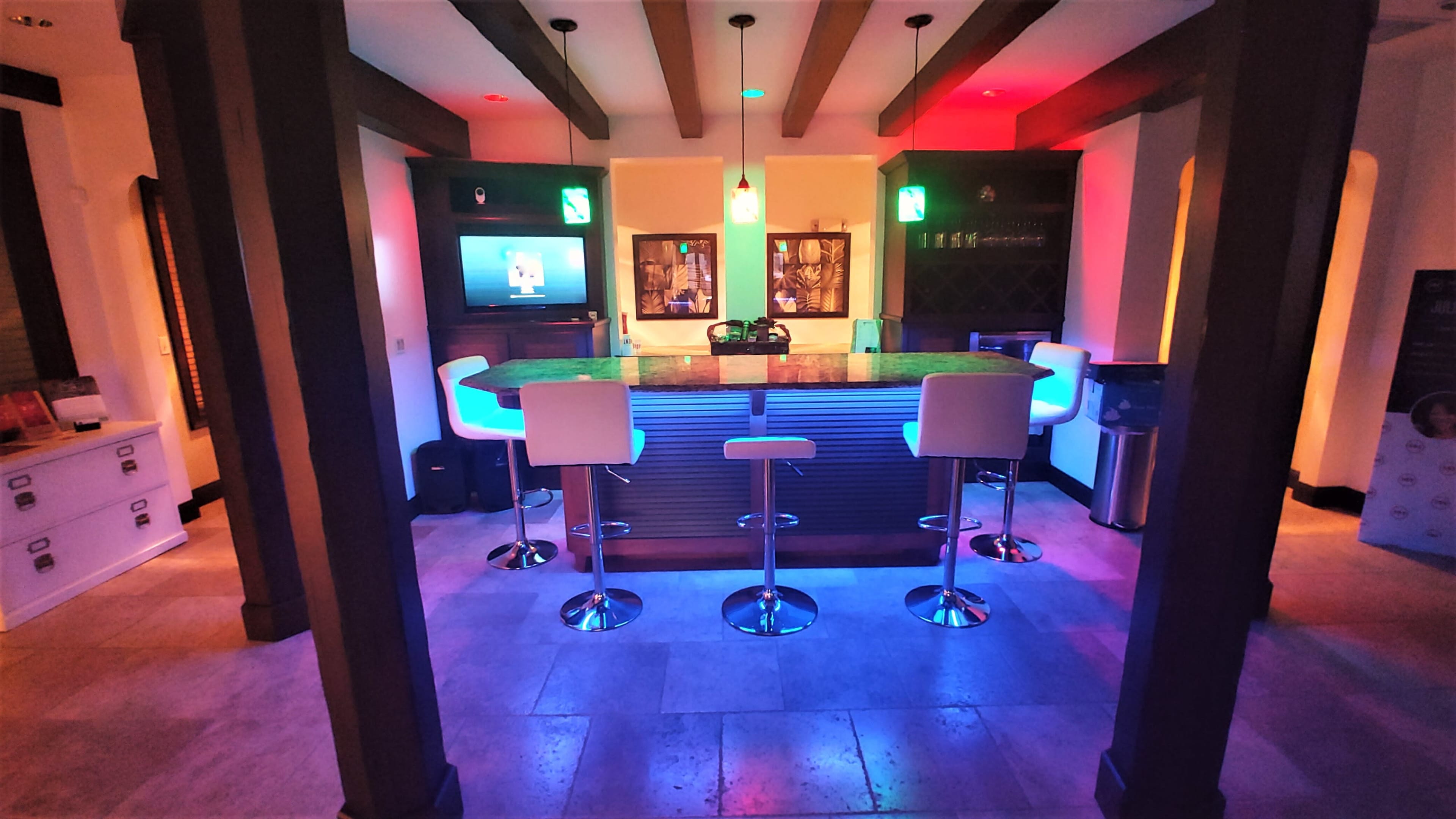 A modern bar area with illuminated seating and a television on the wall.