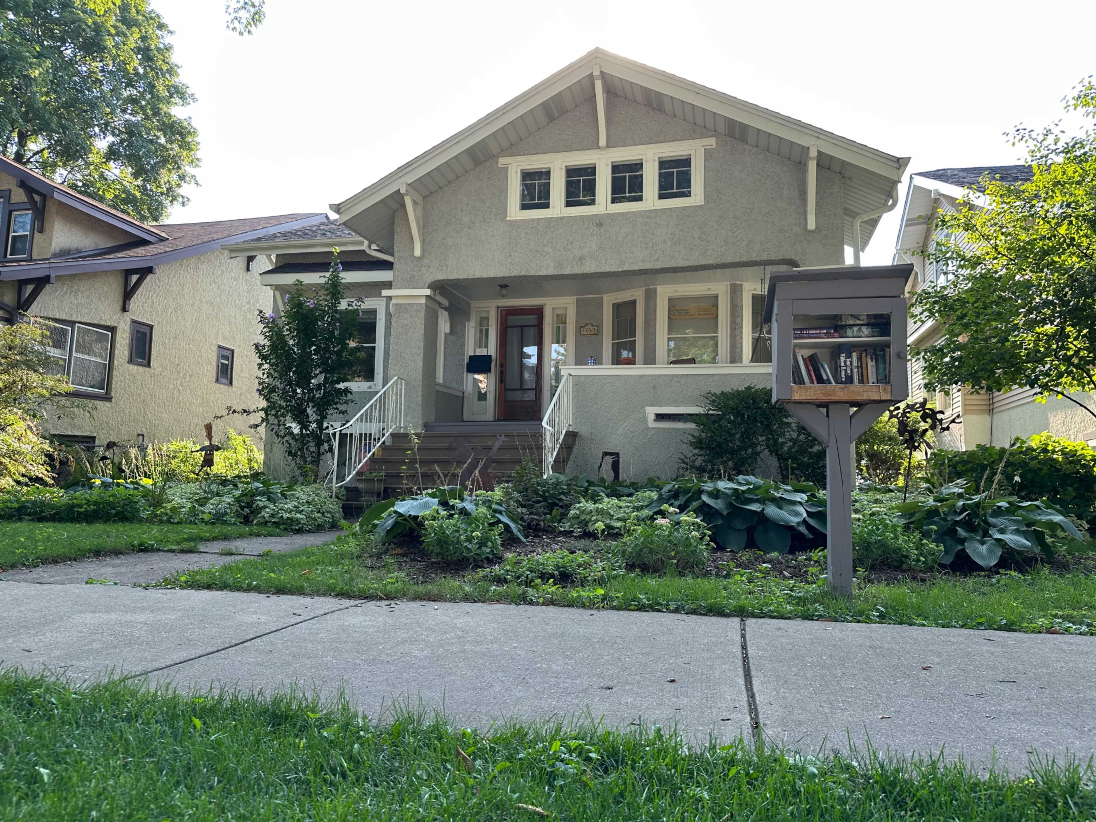 A single-family house with a covered front porch, surrounded by well-maintained landscaping and a mailbox at the edge of the lawn.