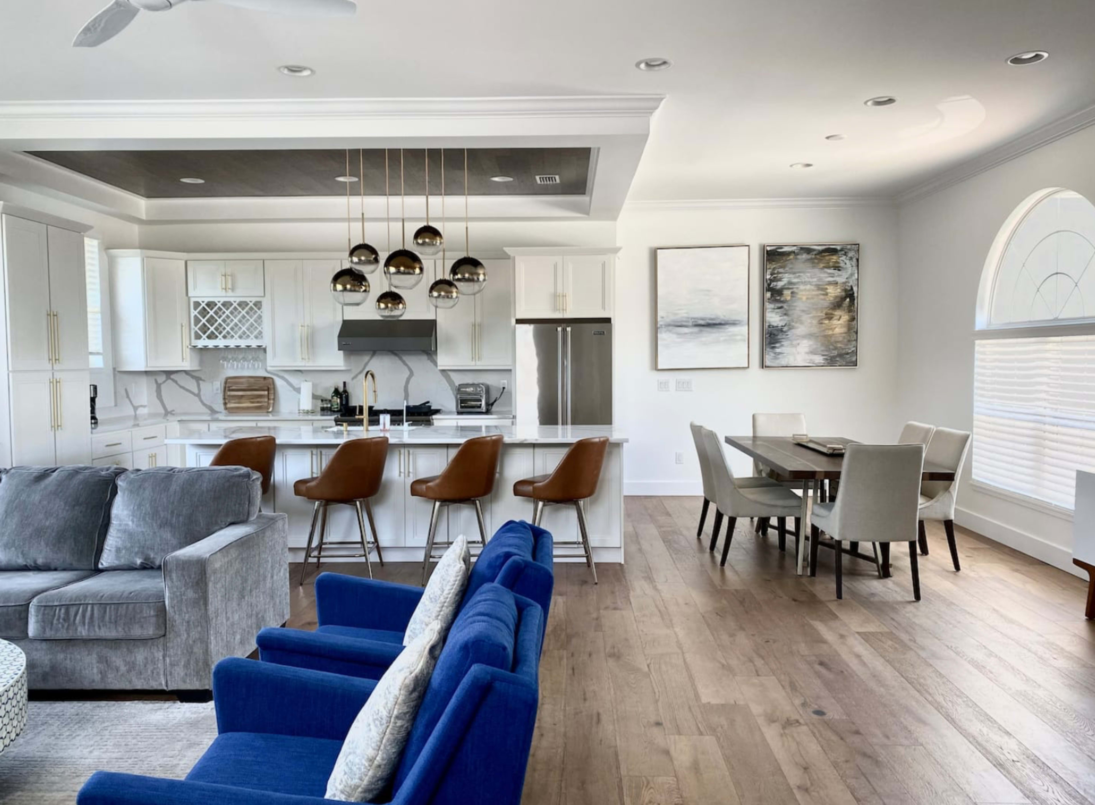A modern kitchen and dining area with a seating arrangement, featuring a kitchen island with bar stools and a dining table nearby.