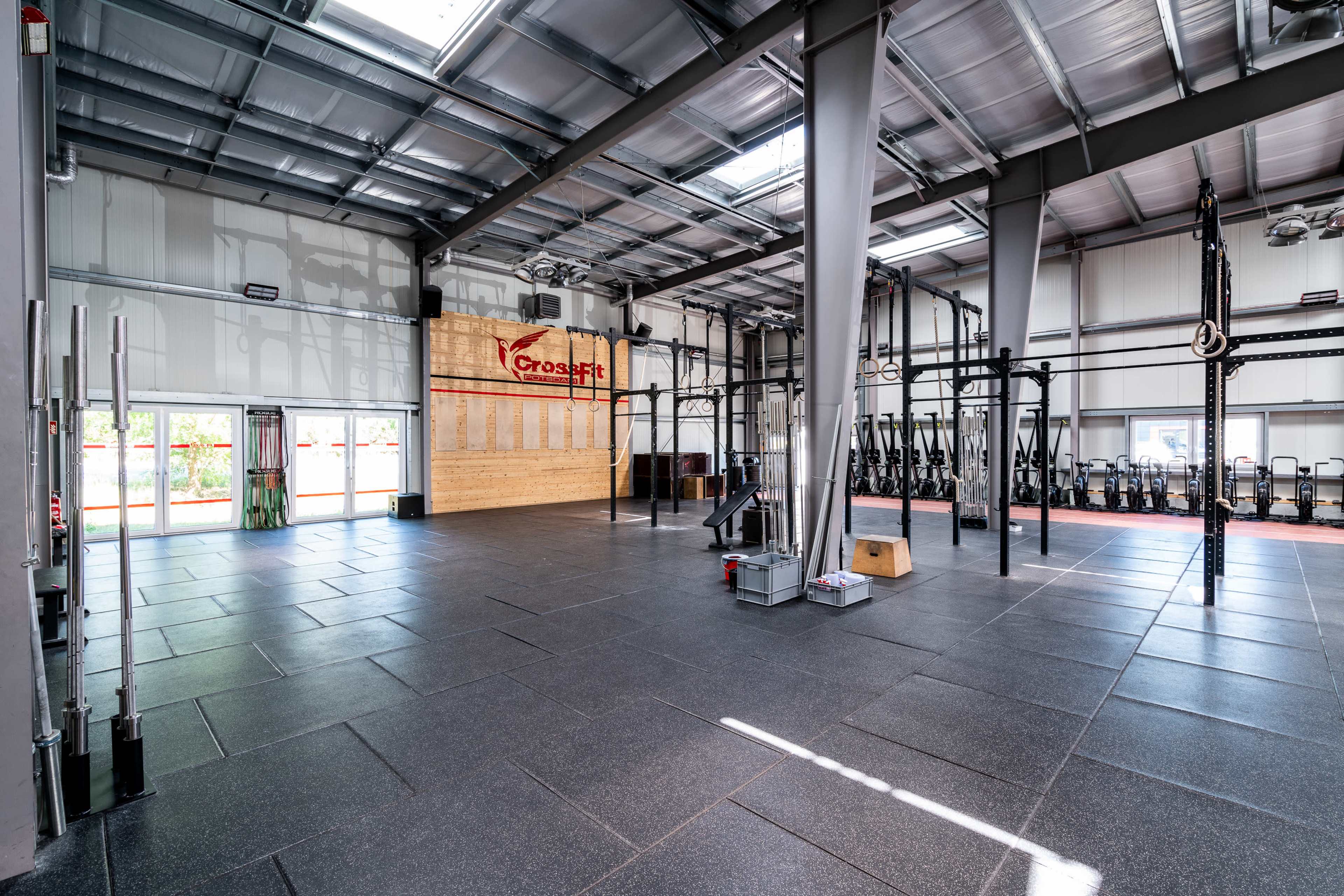 An empty CrossFit gym with various exercise equipment and open space for workouts.