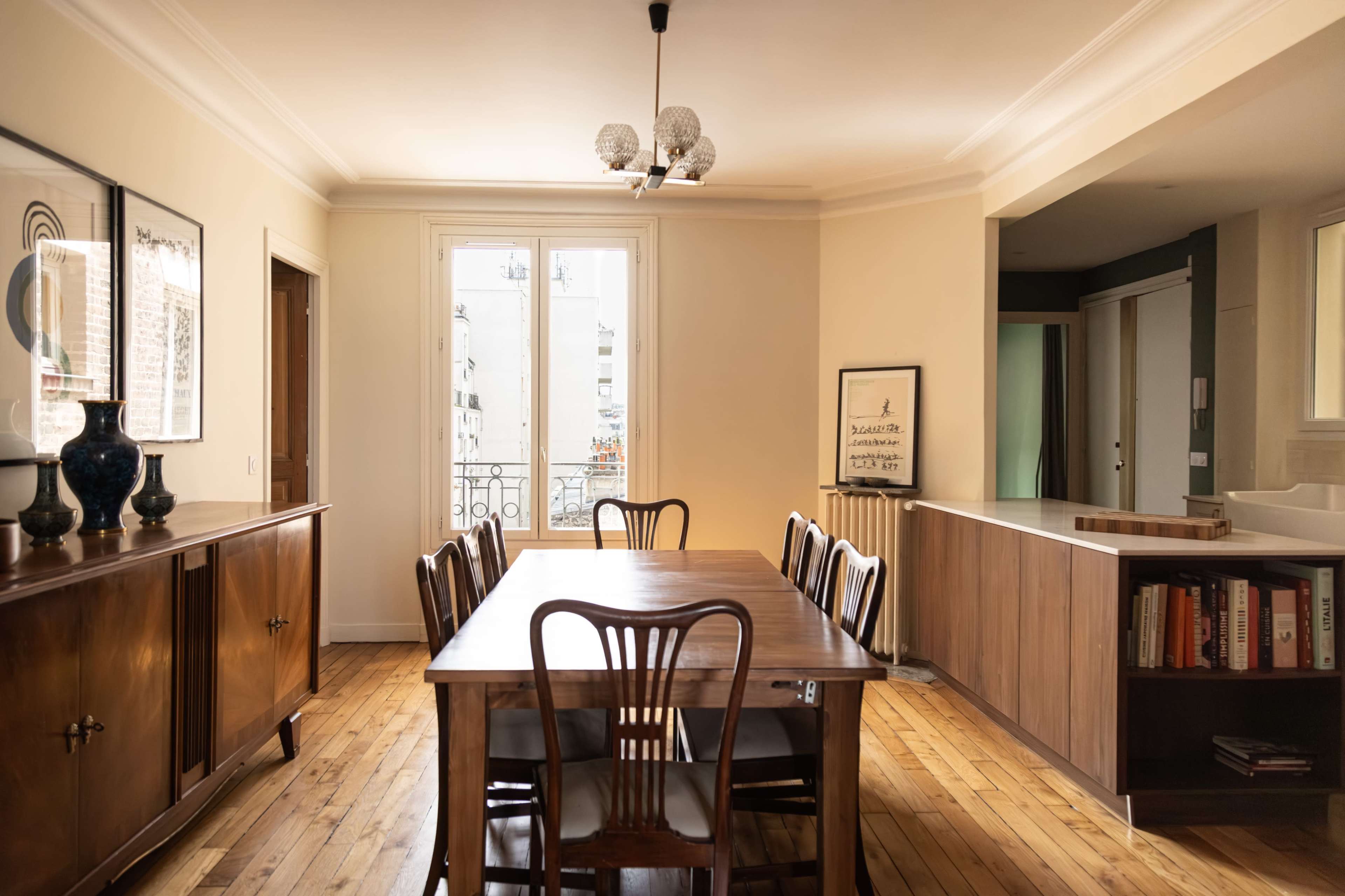 A spacious dining area features a large wooden table surrounded by chairs, with large windows allowing natural light to illuminate the space.