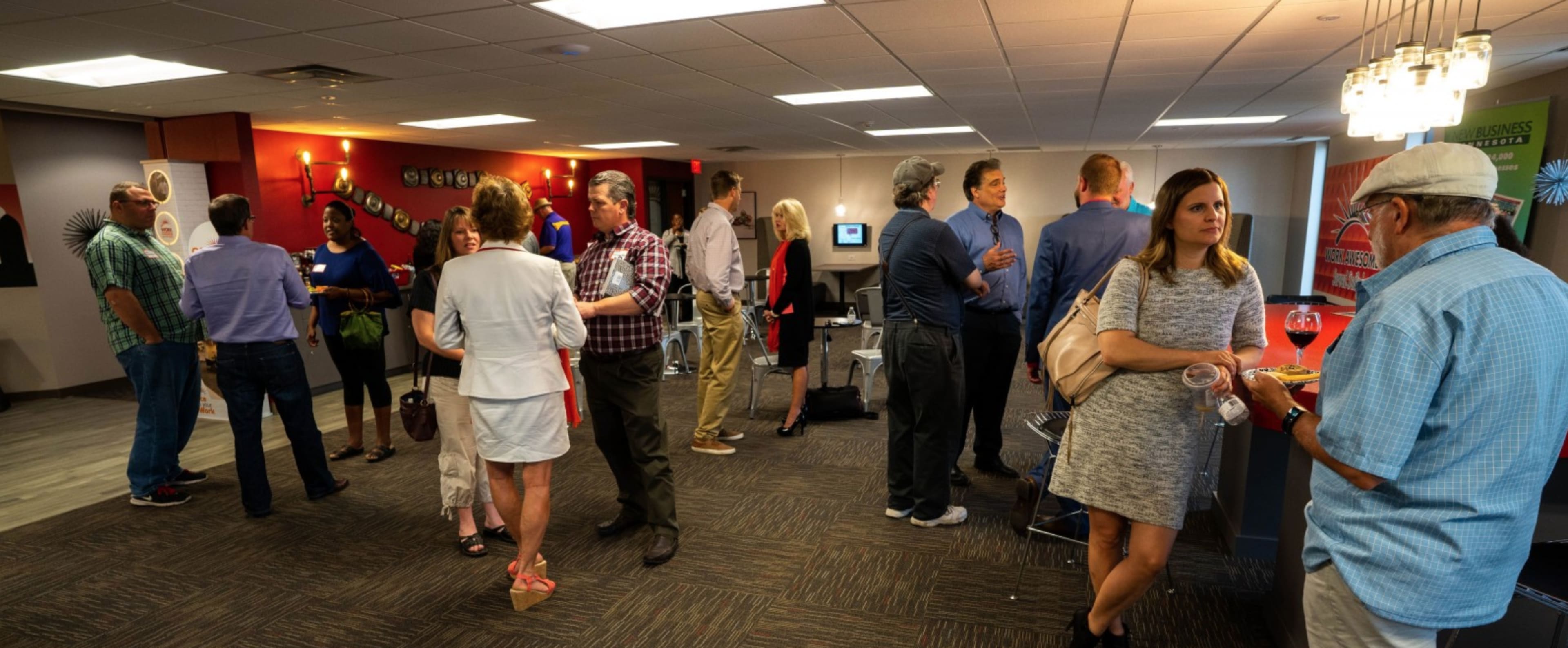 A diverse group of people engages in conversation at a networking event in a modern office space.