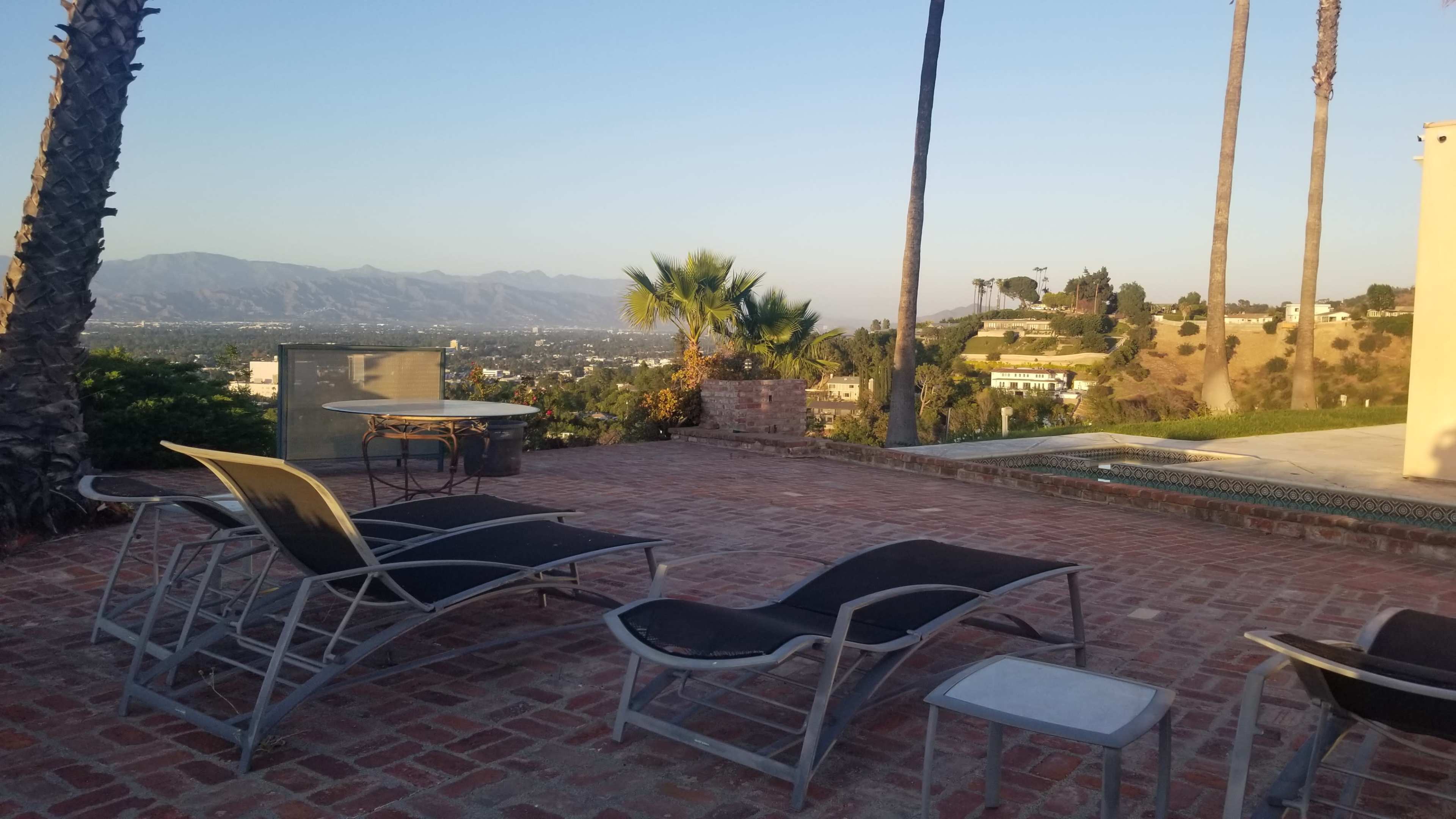 A patio area with lounge chairs overlooking a valley and distant mountains.