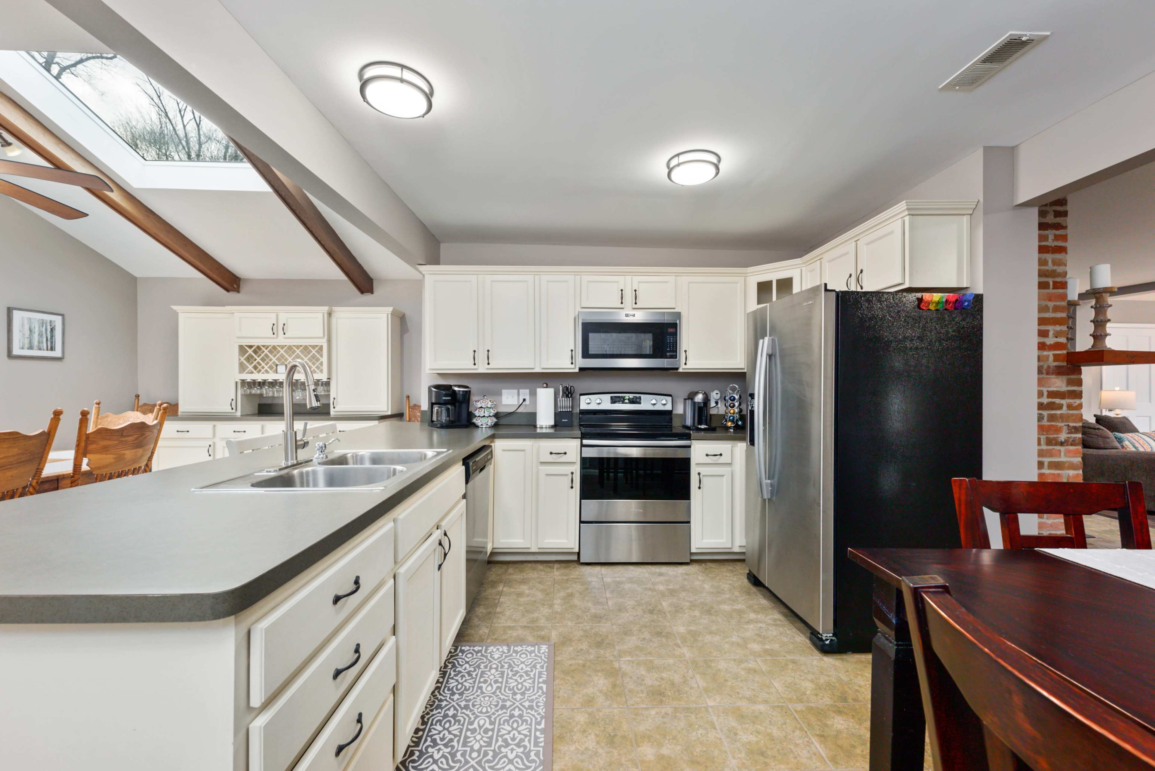 The image shows a modern kitchen with white cabinets, stainless steel appliances, and an island with a sink.