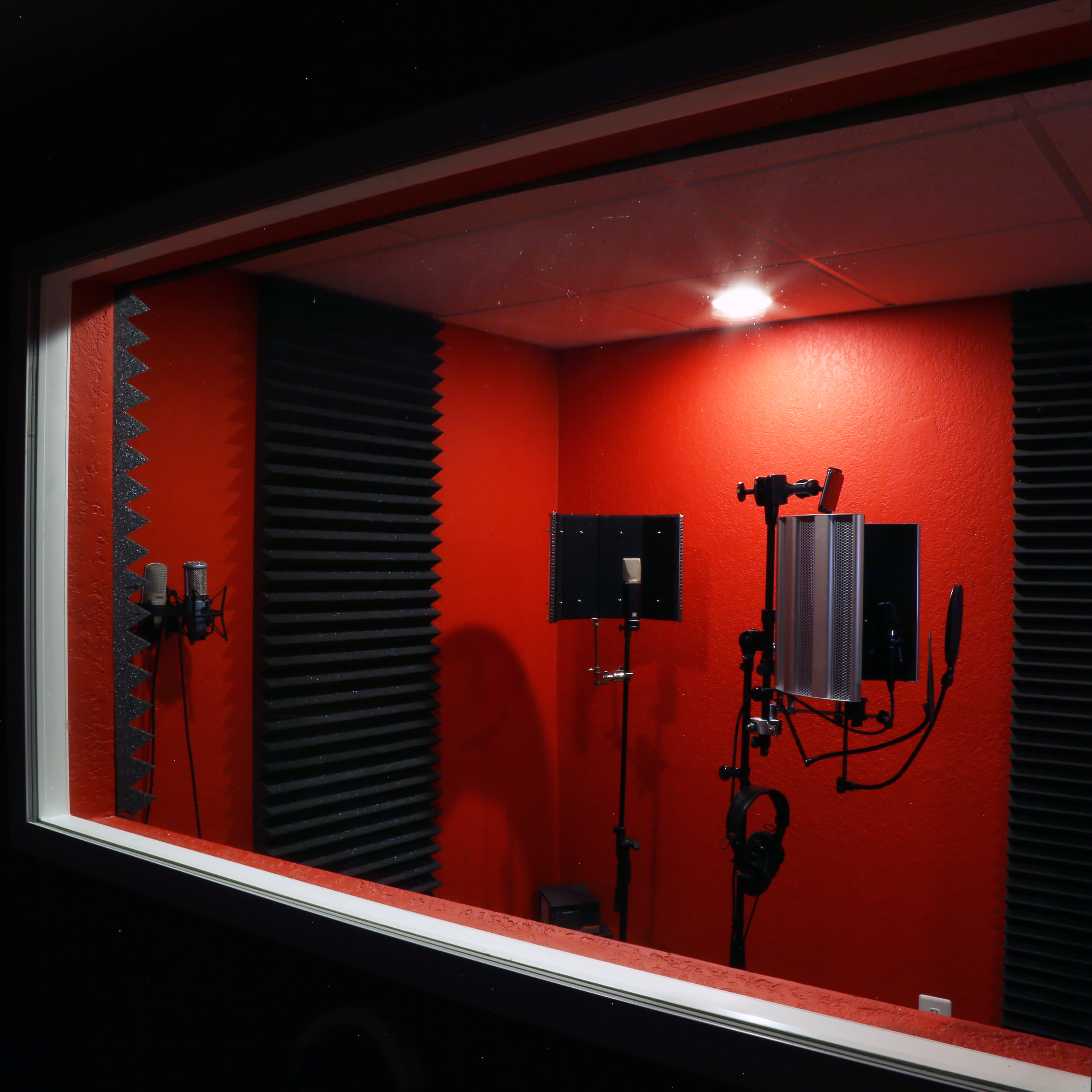 A soundproof recording studio with red walls and black acoustic treatment foam.