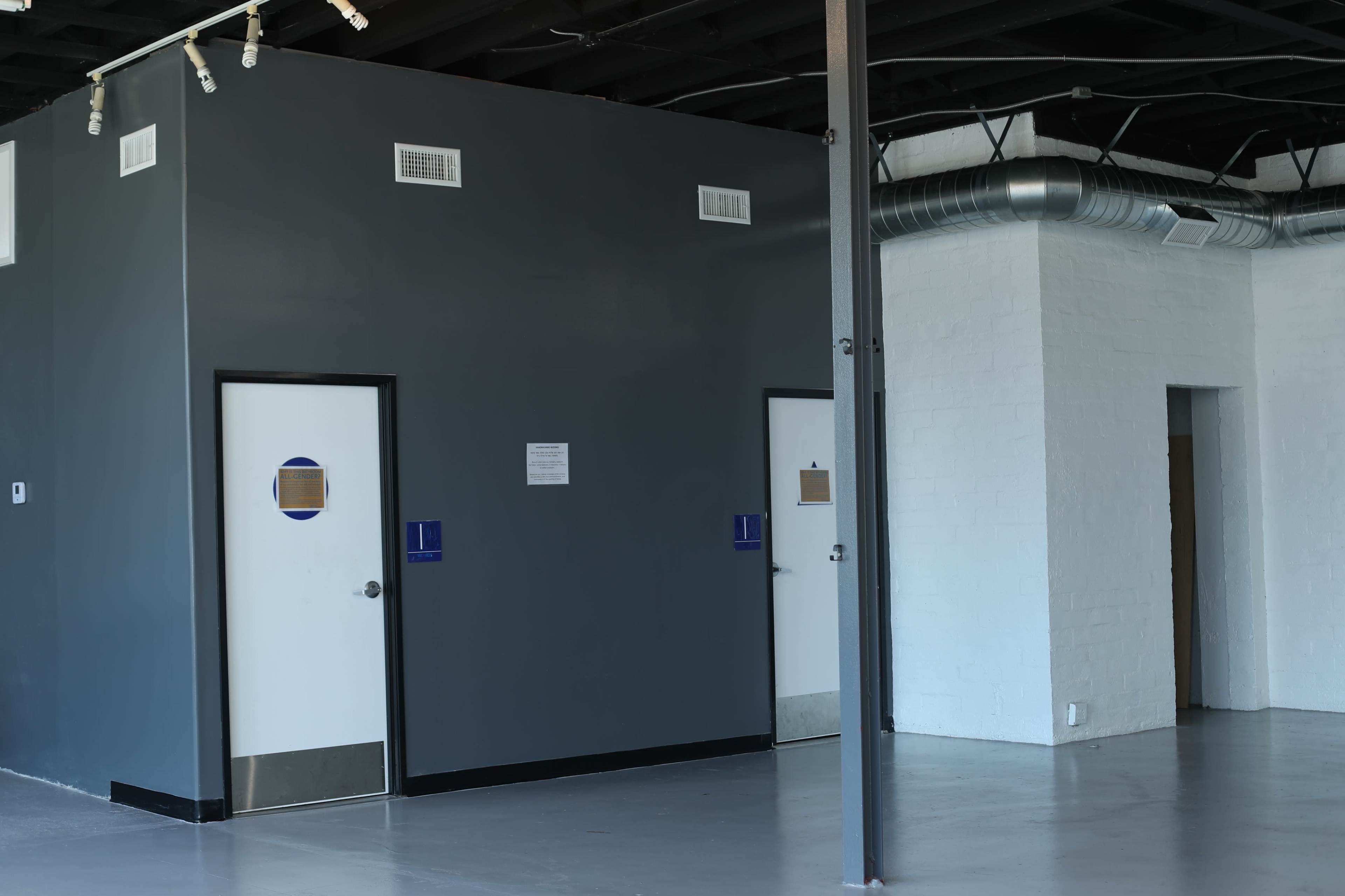 A semi-industrial interior with gray walls and two doors, one on the left and one on the right, along with a white wall in the background.