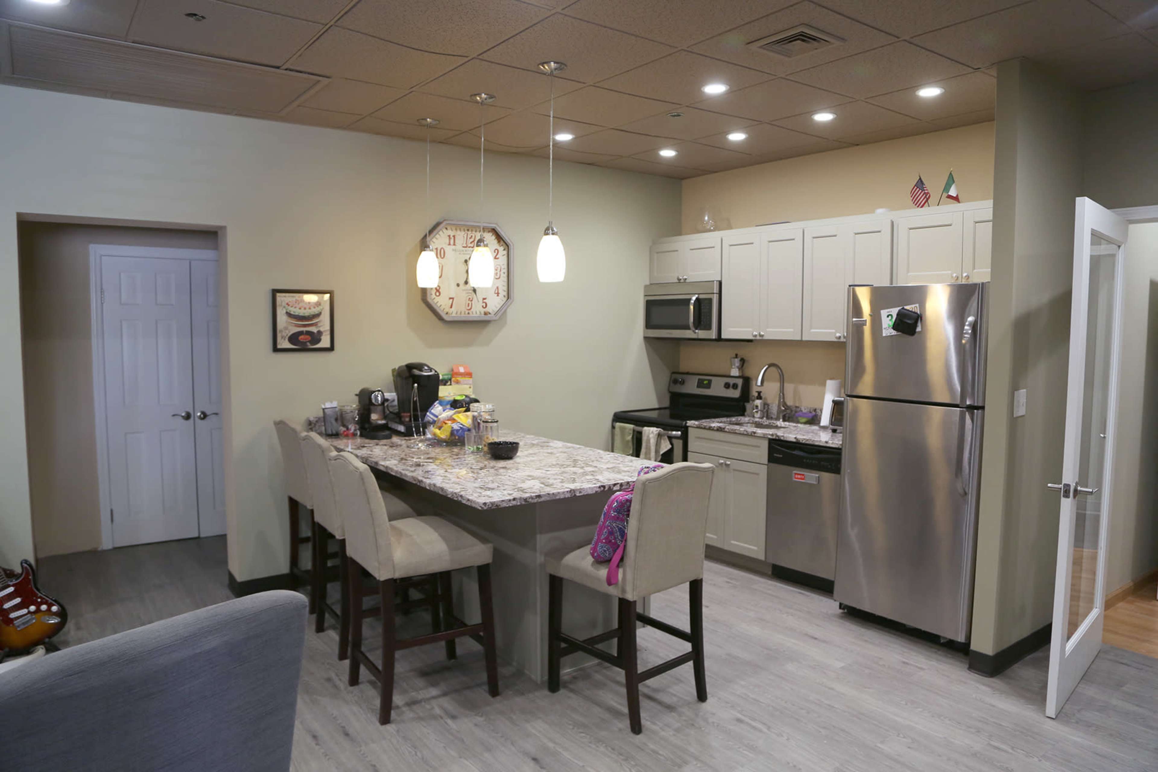 A modern kitchen area with a central island, stainless steel appliances, and light-colored cabinets.