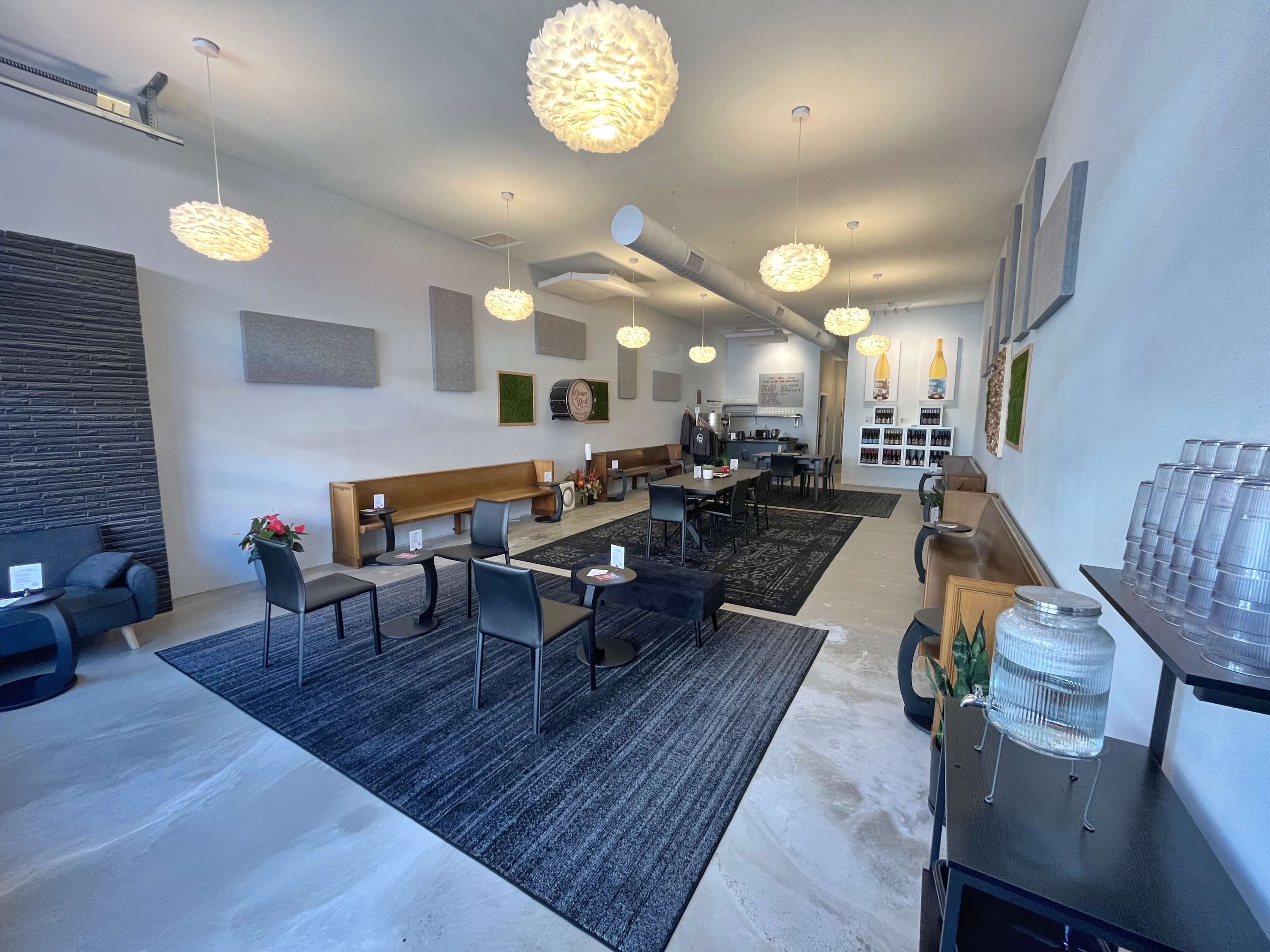 A modern interior of a café with seating arrangements, artwork on the walls, and pendant lights hanging from the ceiling.