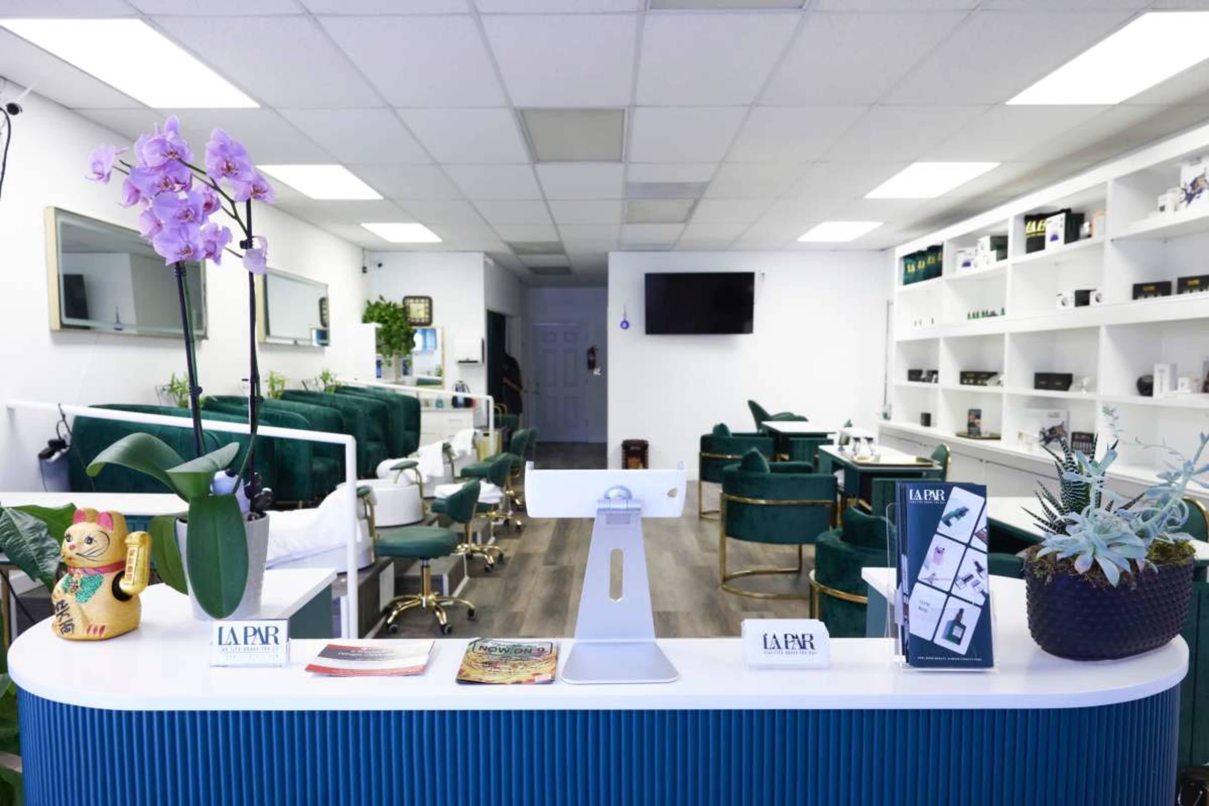 The image shows a modern salon interior with green chairs, a reception area featuring plants and brochures, and a minimalist design.