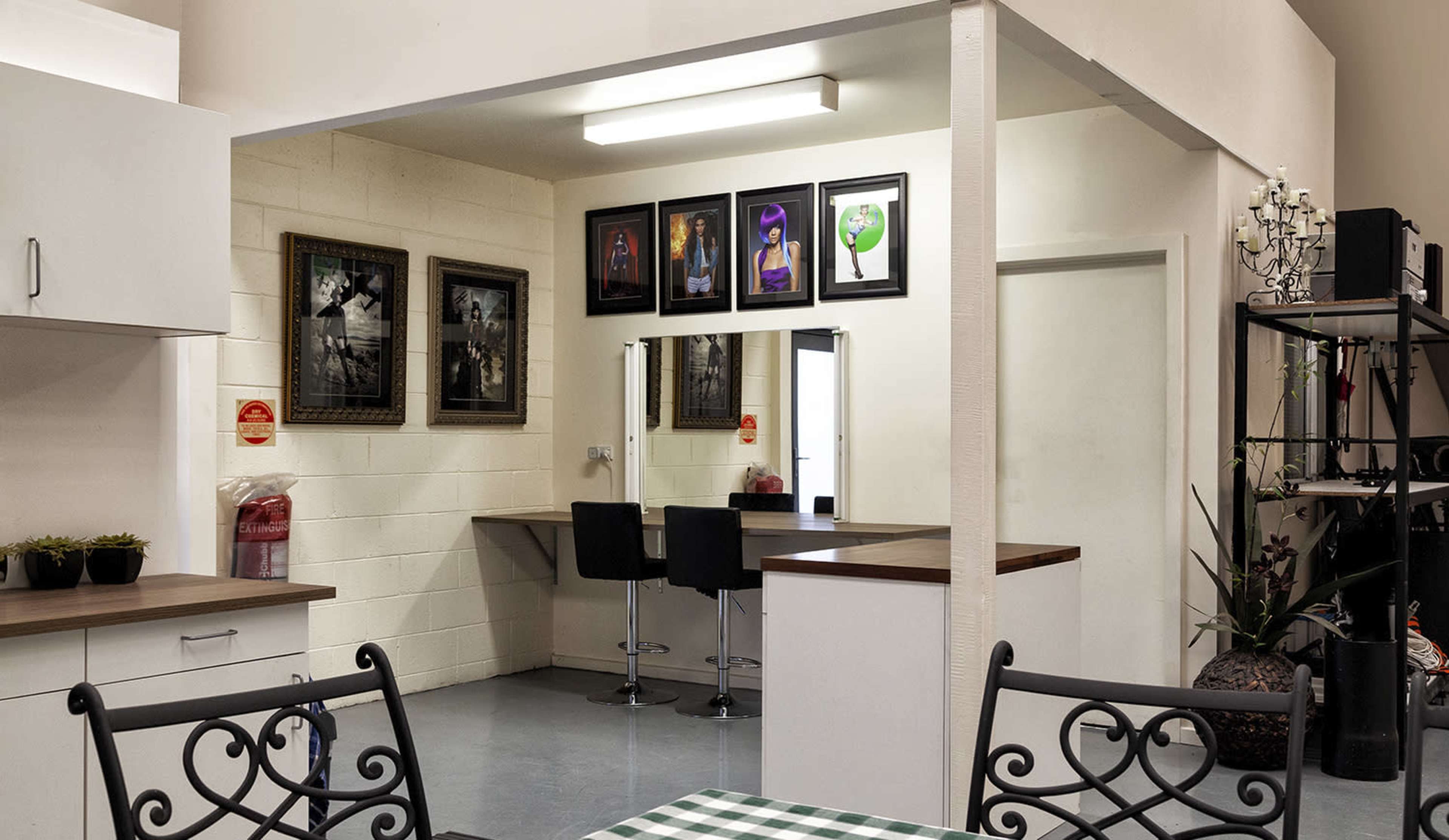 A modern interior space that includes a kitchenette, a seating area with a table, and a wall displaying framed artwork.