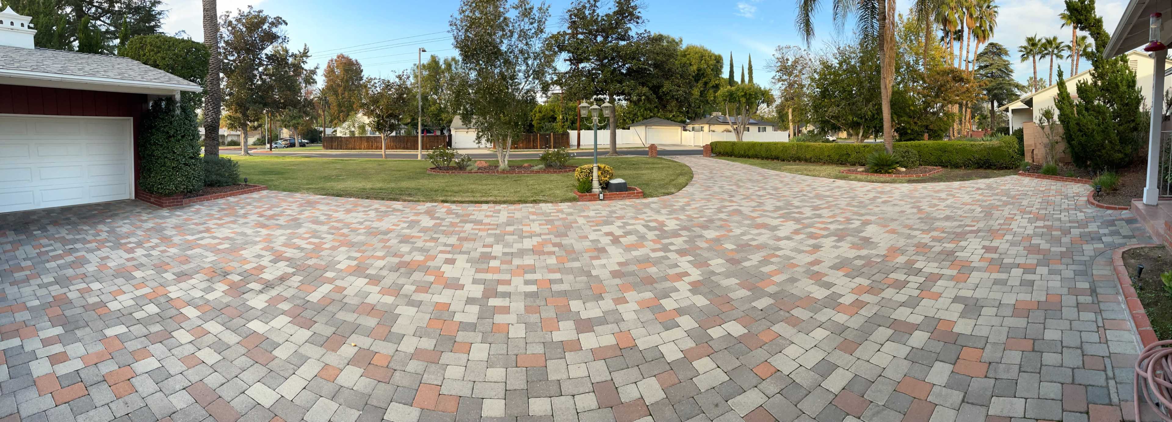 A paved driveway with a circular layout and landscaped garden borders is shown in a residential area.