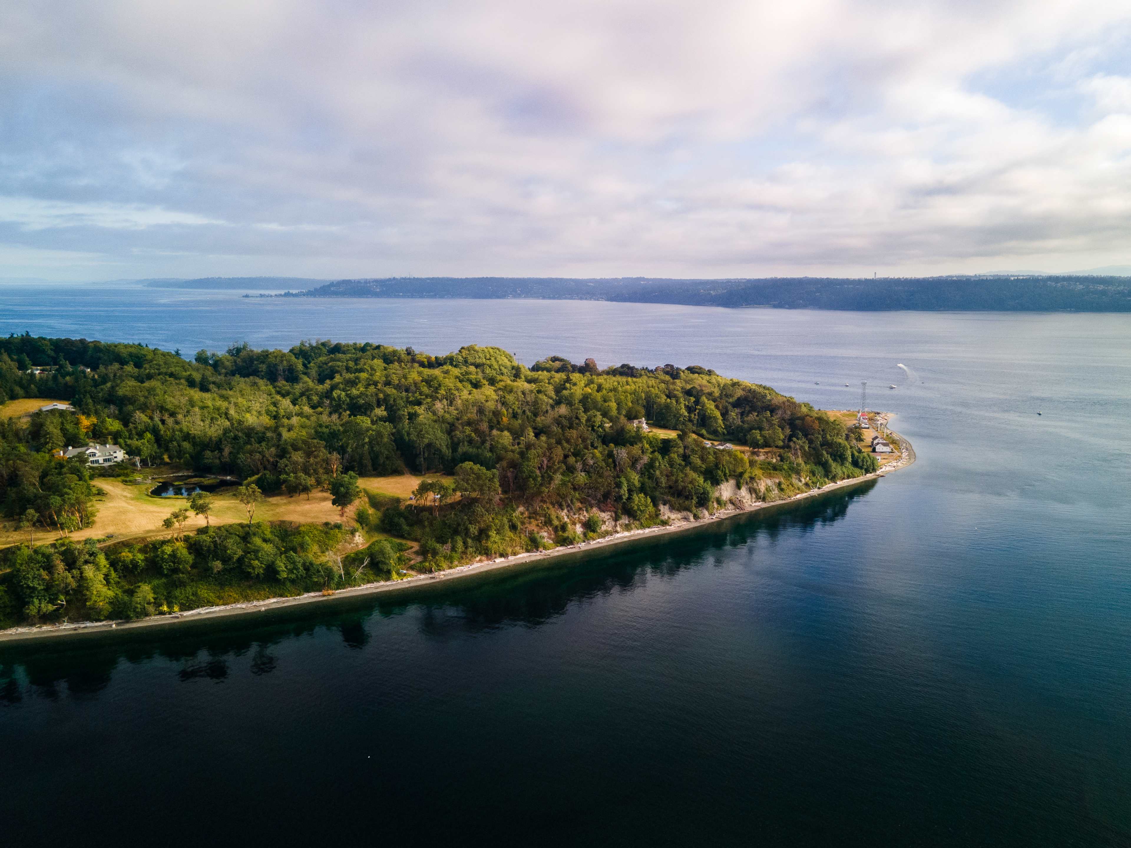 An aerial view of a lush, green island bordered by calm waters and distant hills.
