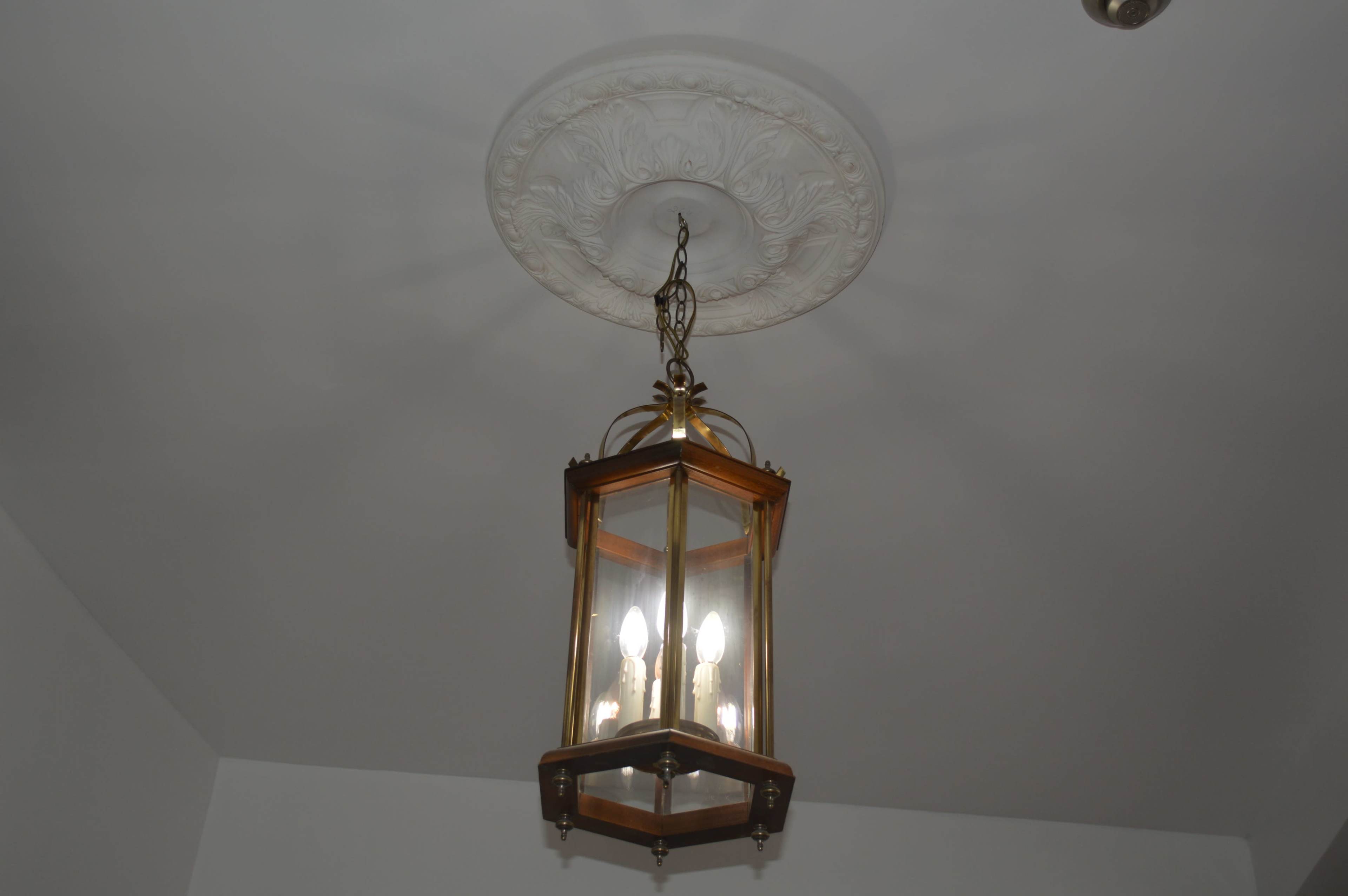 A six-sided, glass lantern hangs from a decorative ceiling medallion in a room.