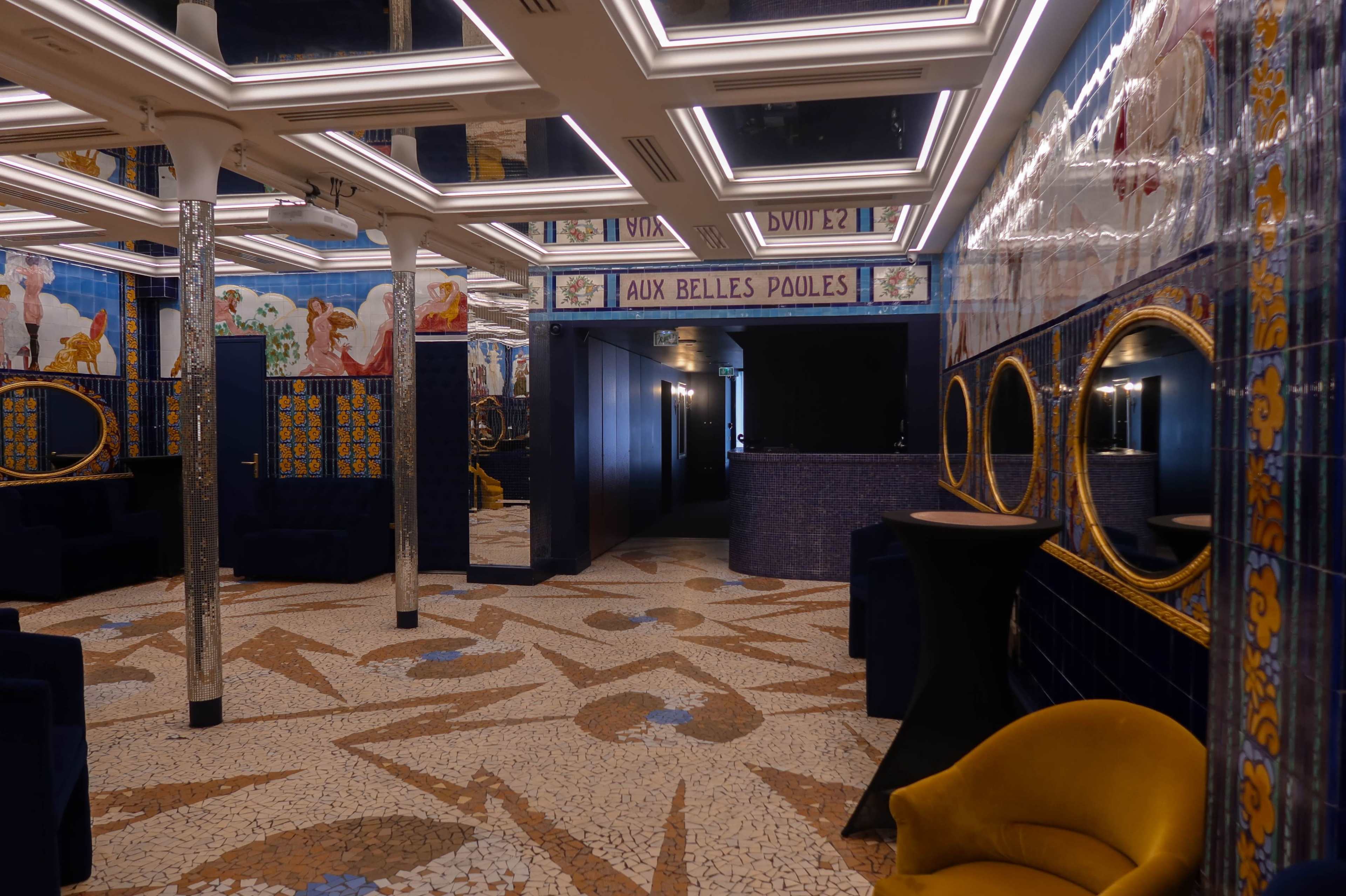 A stylish interior of a tiled room with decorative walls, two mirrors, and distinct seating areas.