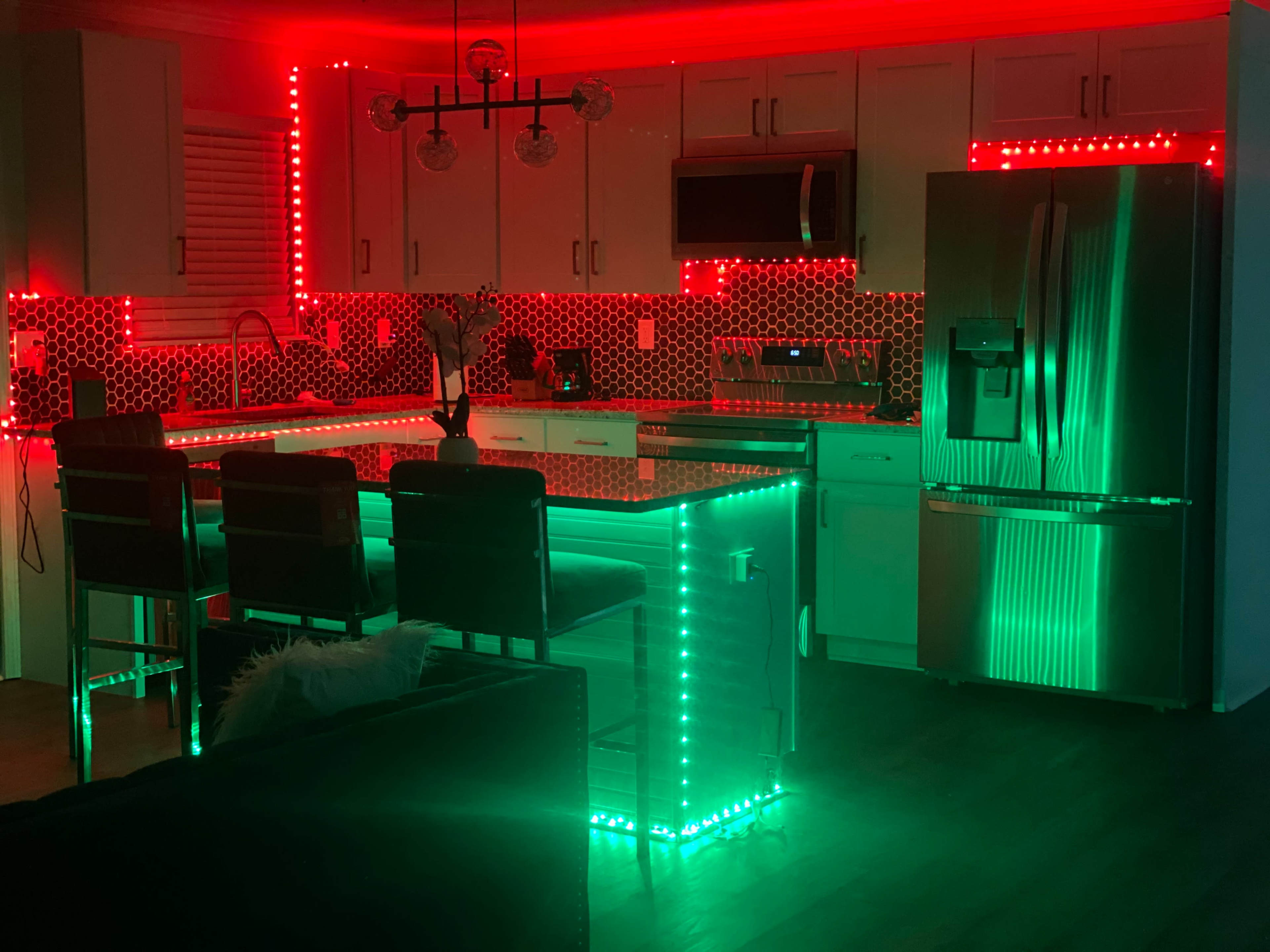 The kitchen features modern cabinets and appliances, illuminated with red and green LED lights outlining the countertops and back walls.