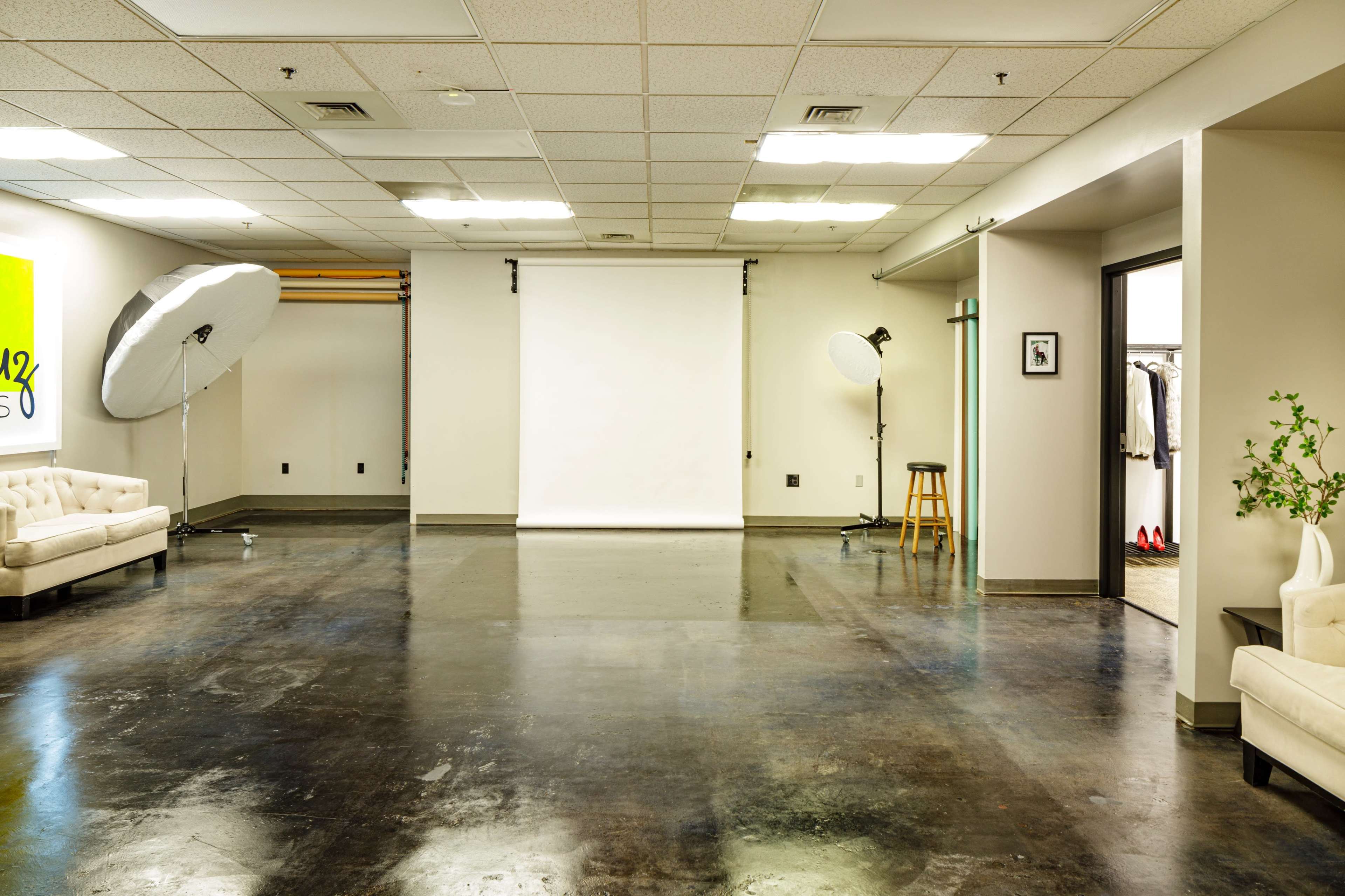 A spacious studio with two large softbox lights, a backdrop, and a seating area.