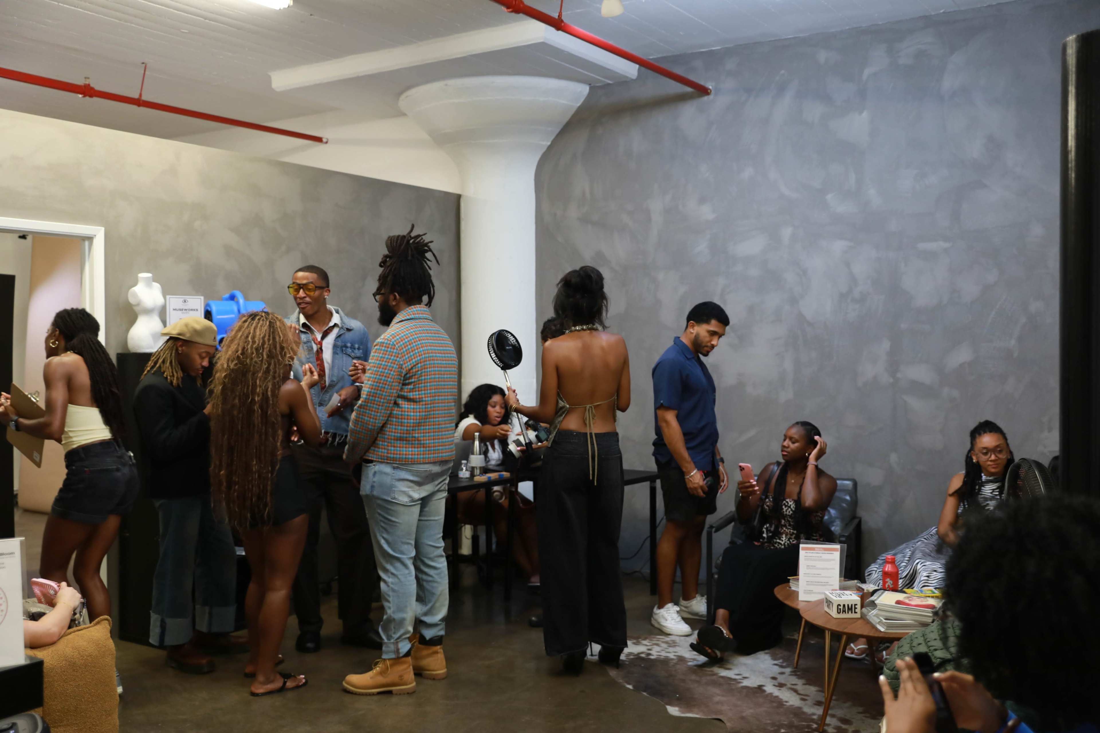 A group of people socialize in a modern indoor space with gray walls and various seating arrangements.