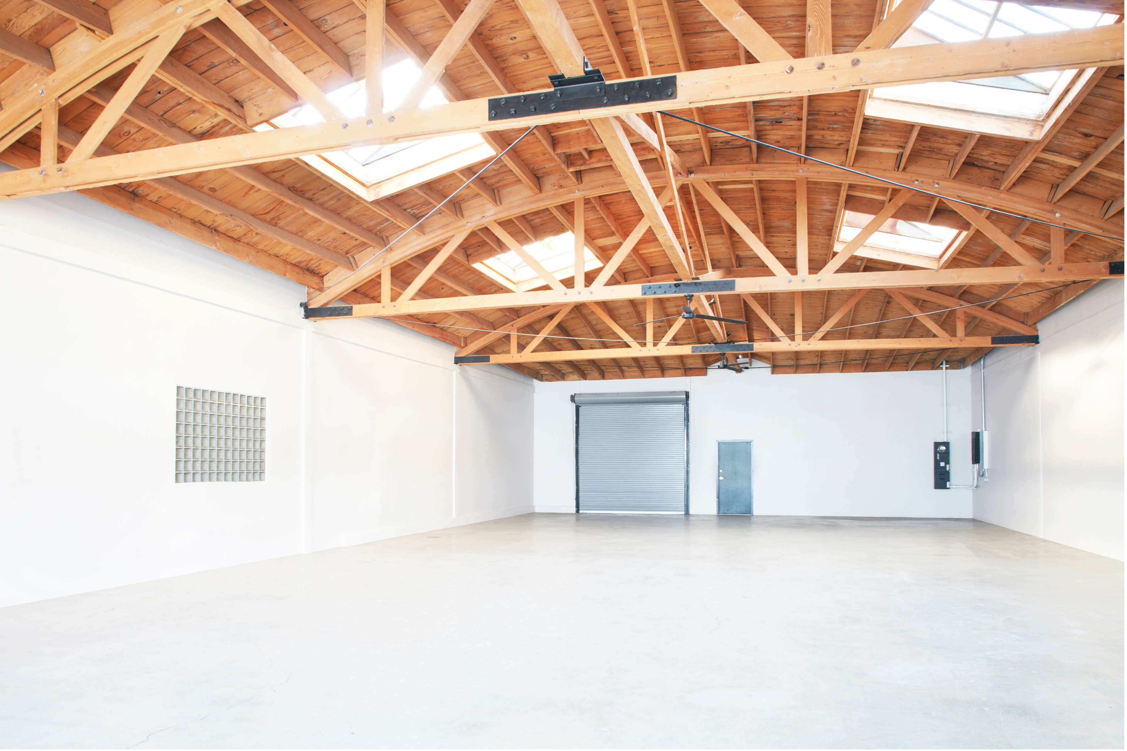 A spacious, empty room with a high wooden ceiling and large skylights.